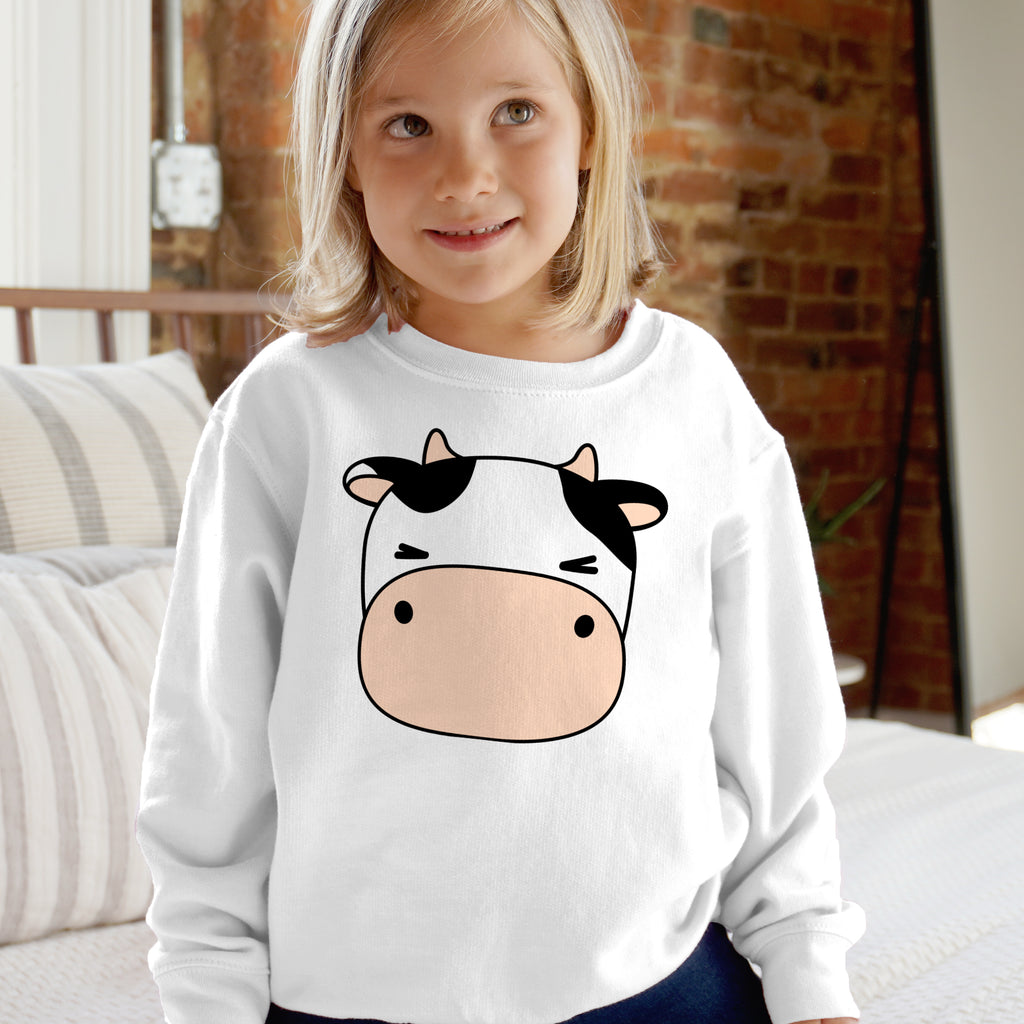 White long-sleeved kids sweatshirt with a cartoon cow face featuring black patches and a pink snout on the front