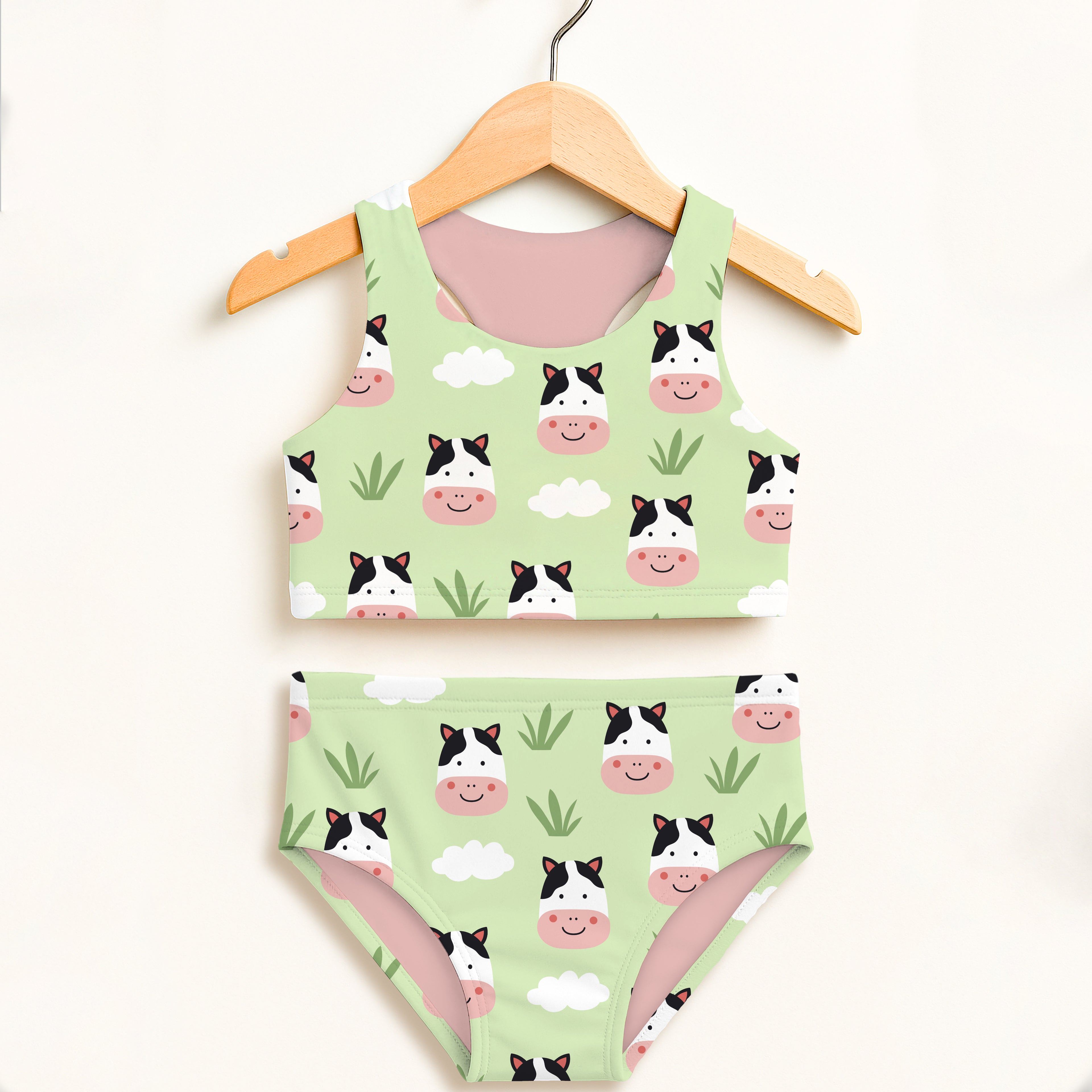 A light green girls cow two piece swimsuit with smiling cartoon cows and clouds features double layered upf 50+ fabric