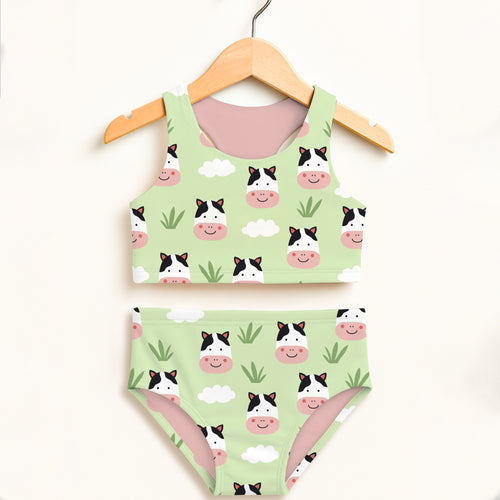 A light green girls cow two piece swimsuit with smiling cartoon cows and clouds features double layered upf 50+ fabric