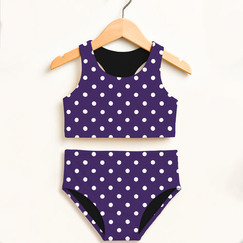Girls dark purple polka dot two piece swimsuit with white dots and black lining hanging on wooden hanger