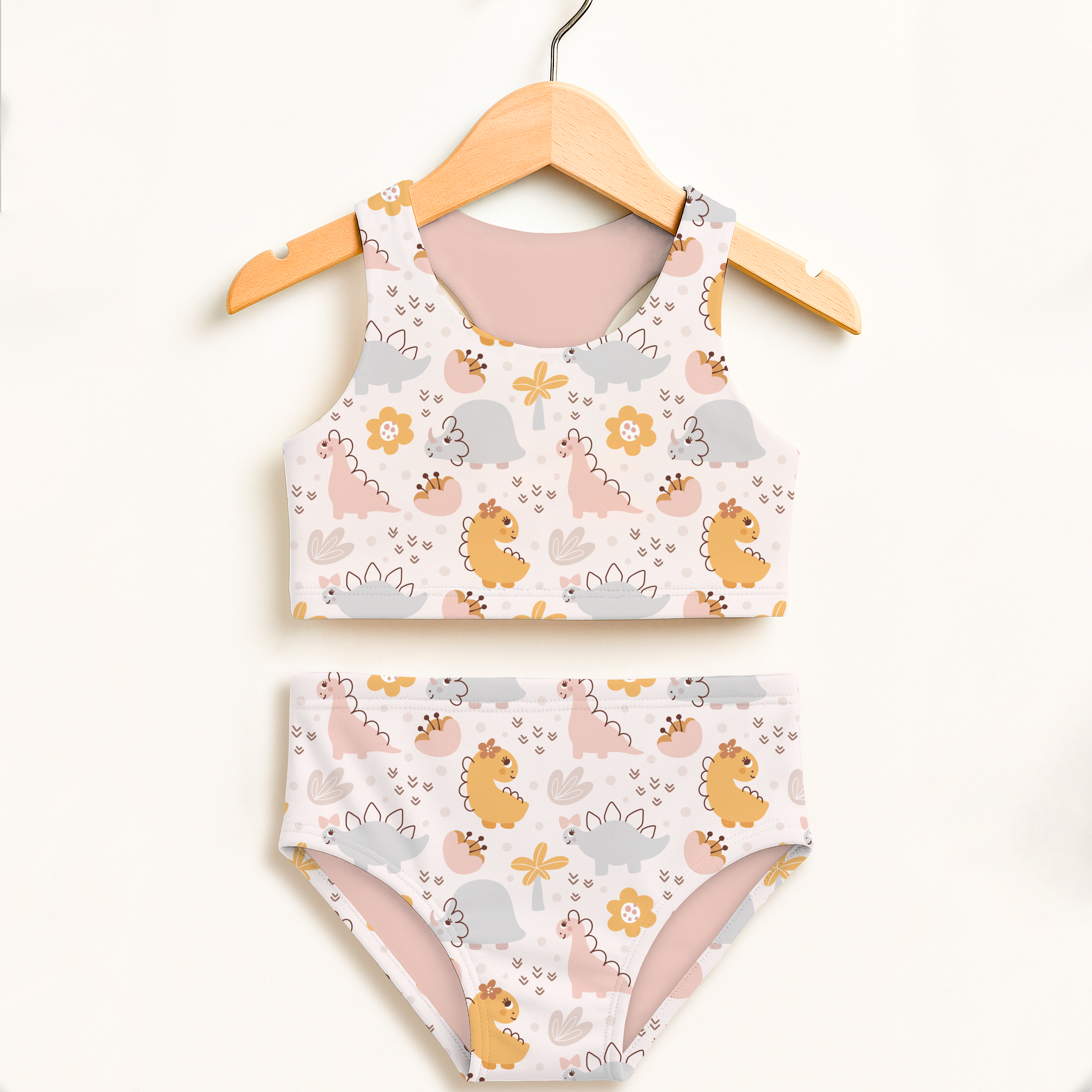Girls floral dinosaur two piece swimsuit with playful pastel dinosaur print white fabric soft pink lining upf 50+ protection
