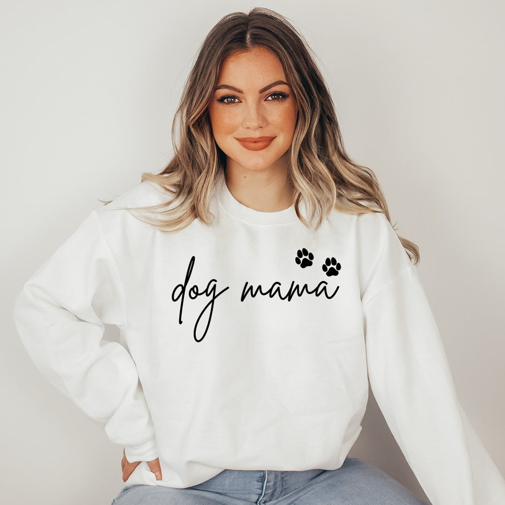 Woman wearing a white sweatshirt with 'dog mama' text and paw prints on a plain background