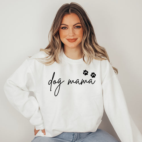 Woman wearing a white sweatshirt with 'dog mama' text and paw prints on a plain background