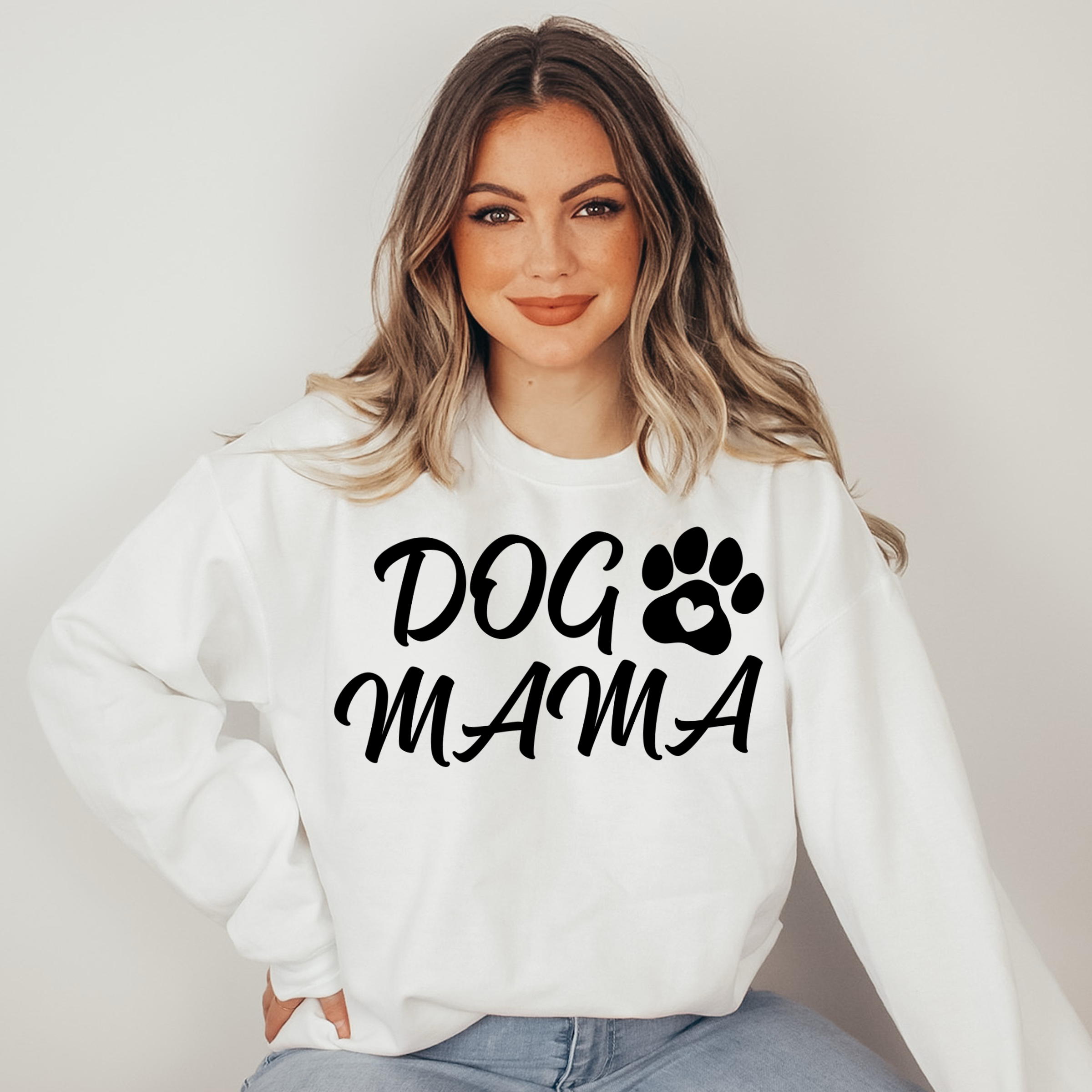 Woman wearing a white sweatshirt with 'DOG MAMA' text and paw print design.