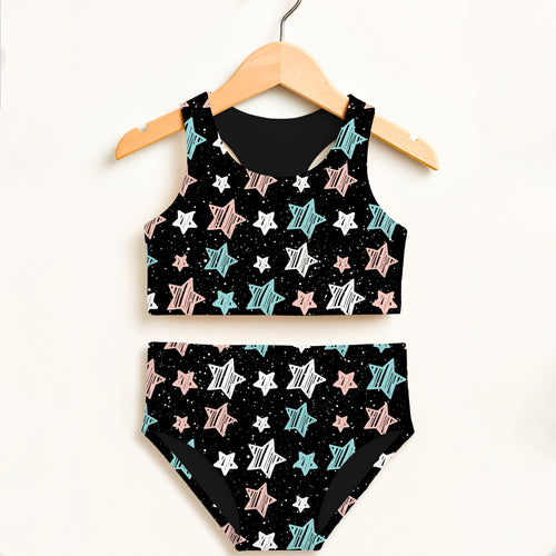 Girls doodle star two piece swimsuit with pastel pink and teal stars on black fabric displayed on wooden hanger