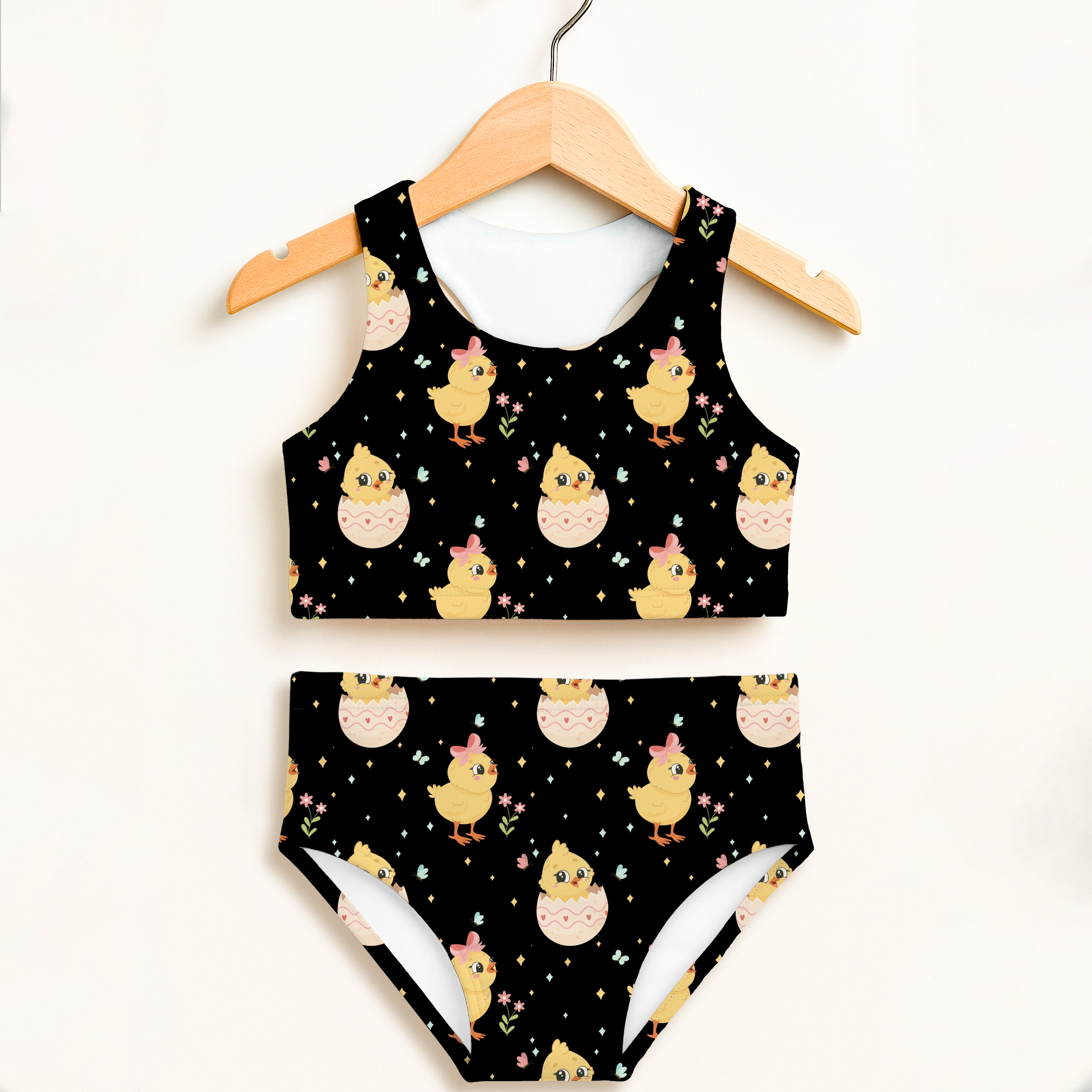 Girls black two-piece swimsuit with double layered upf 50 plus featuring yellow chicks with pink bows and eggshells on stars
