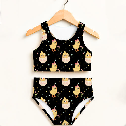 Girls black two-piece swimsuit with double layered upf 50 plus featuring yellow chicks with pink bows and eggshells on stars