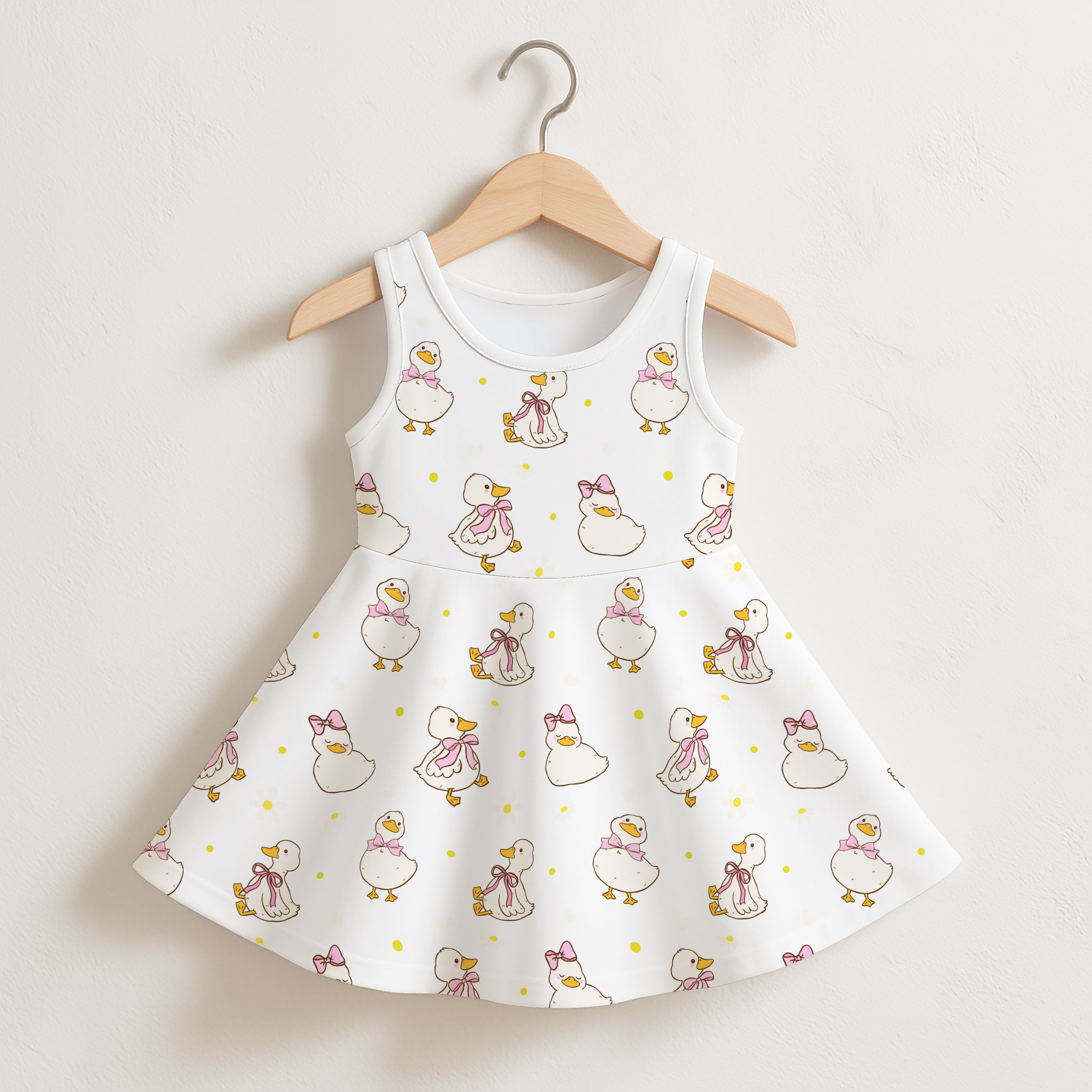 White sleeveless girls dress with flared skirt featuring playful cartoon ducks with pink bows and yellow polka dots