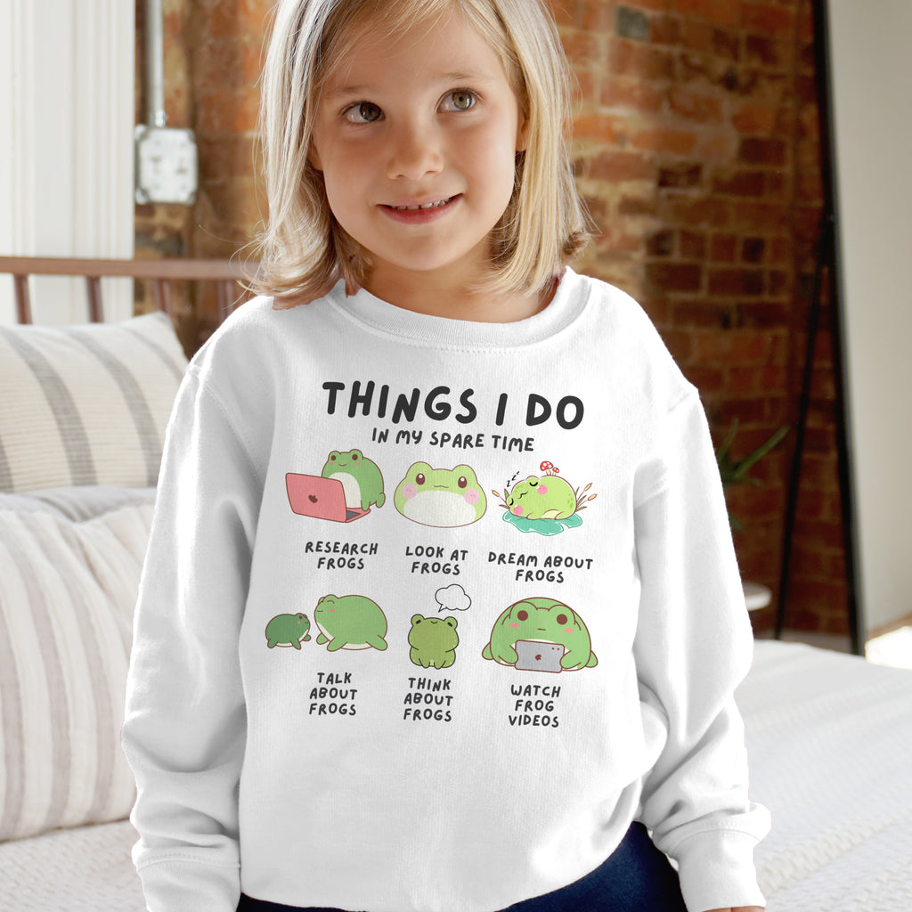 Child wearing a white sweatshirt with frog-themed text and graphics