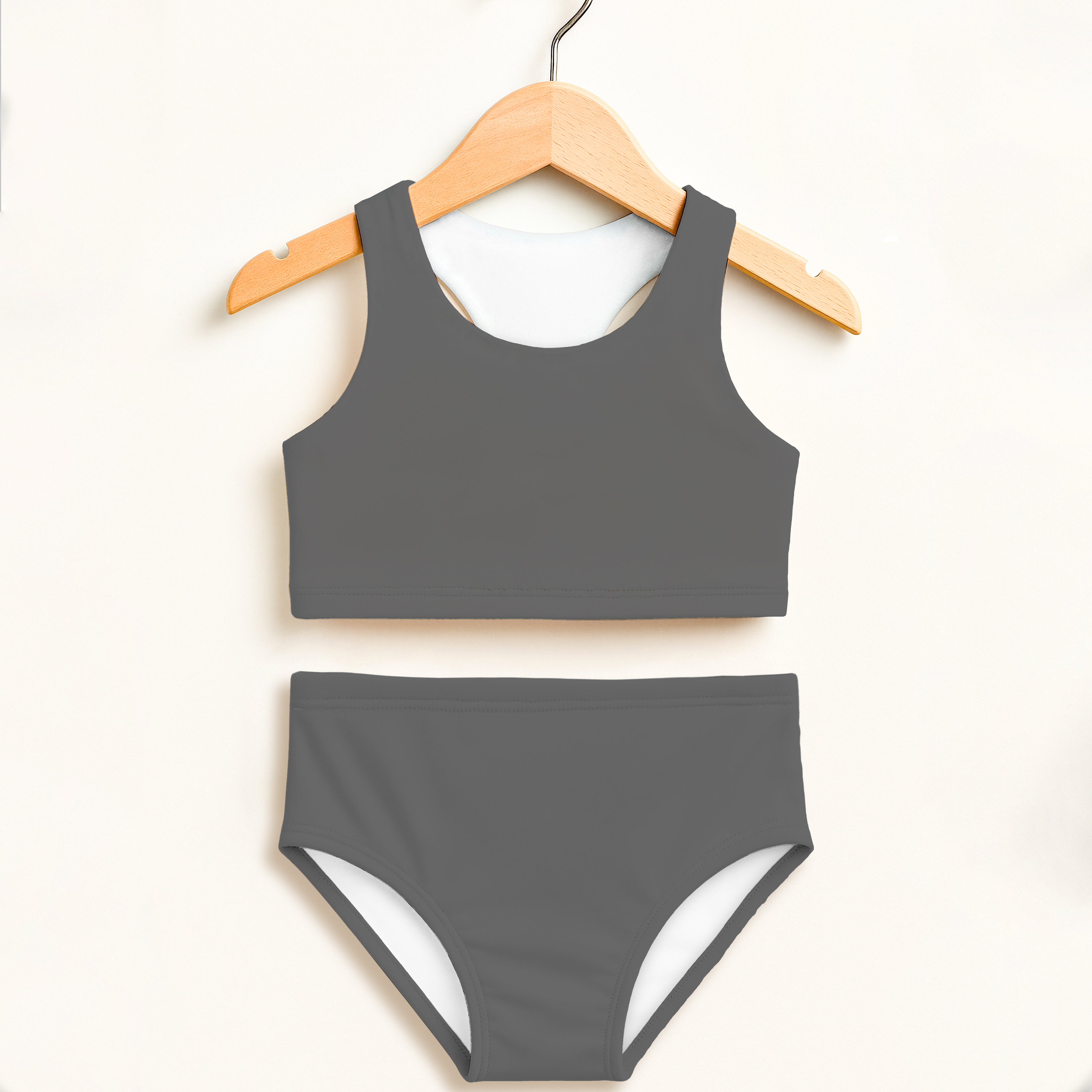Girls gray two piece swimsuit with white lining on sides and back hanging on wooden hanger showing back side