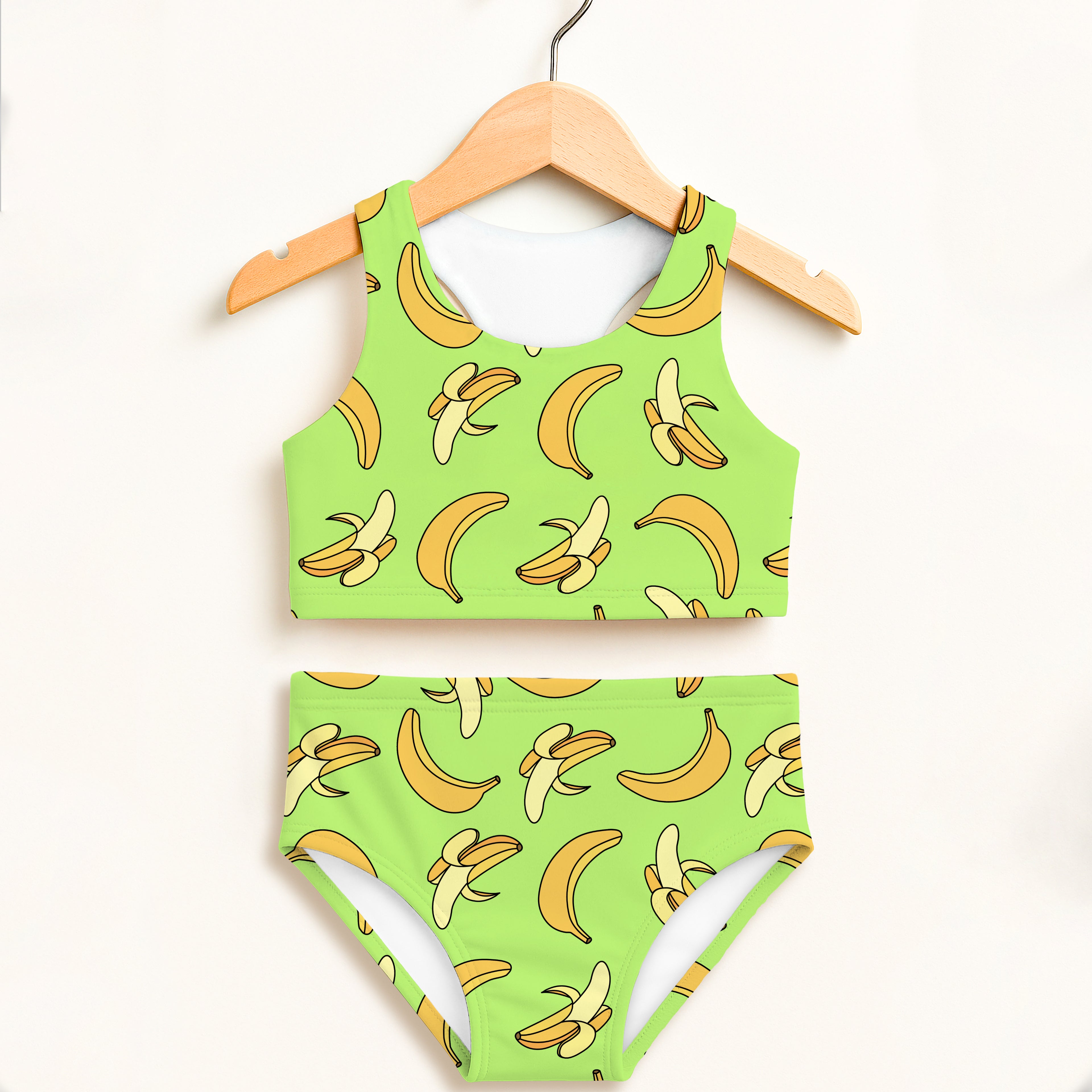 Girls green banana print two-piece swimsuit hanging on wooden hanger double layered UPF 50 plus high waisted comfort