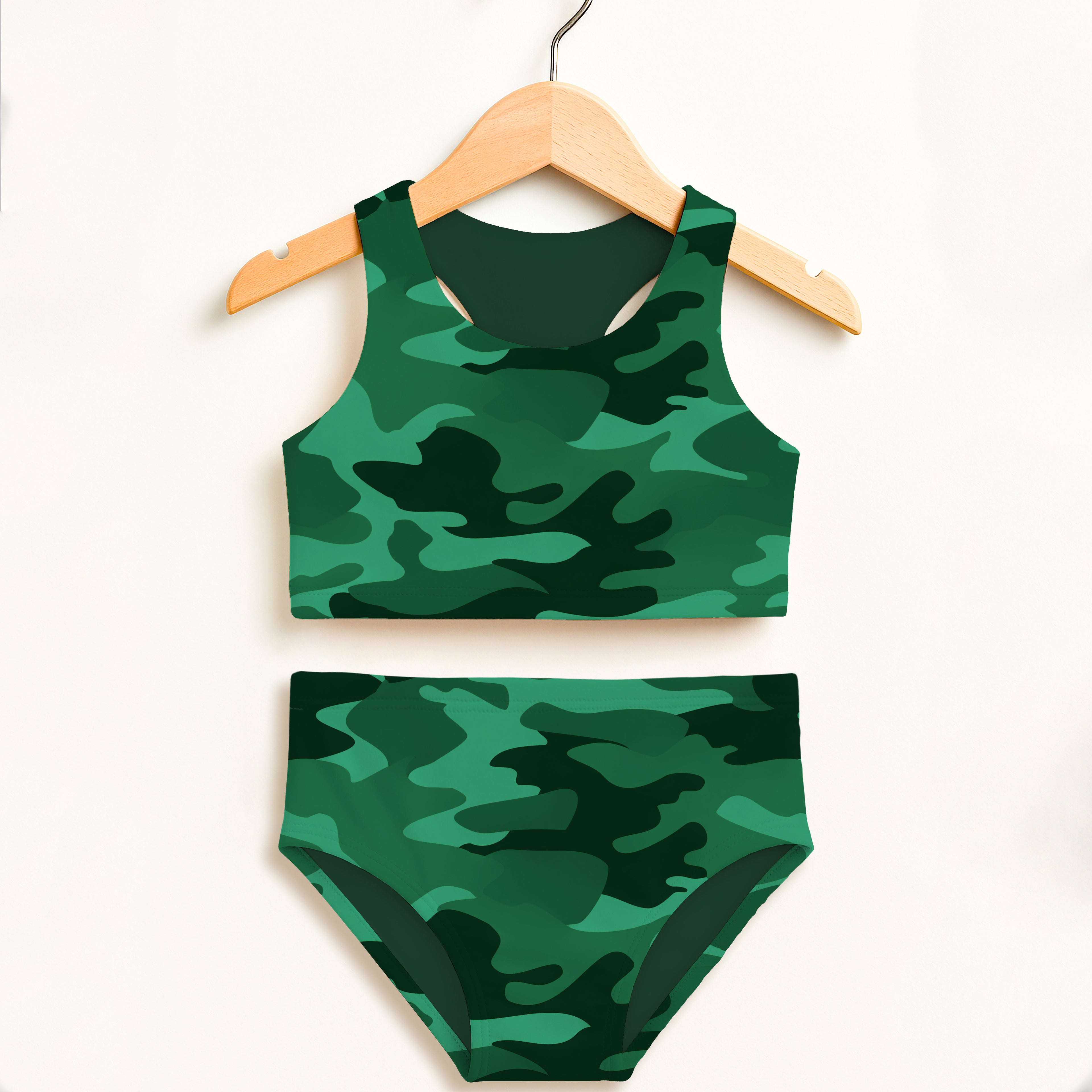 Girls dark green camouflage two-piece swimsuit with double layered upf 50+ fabric hanging on wooden hanger