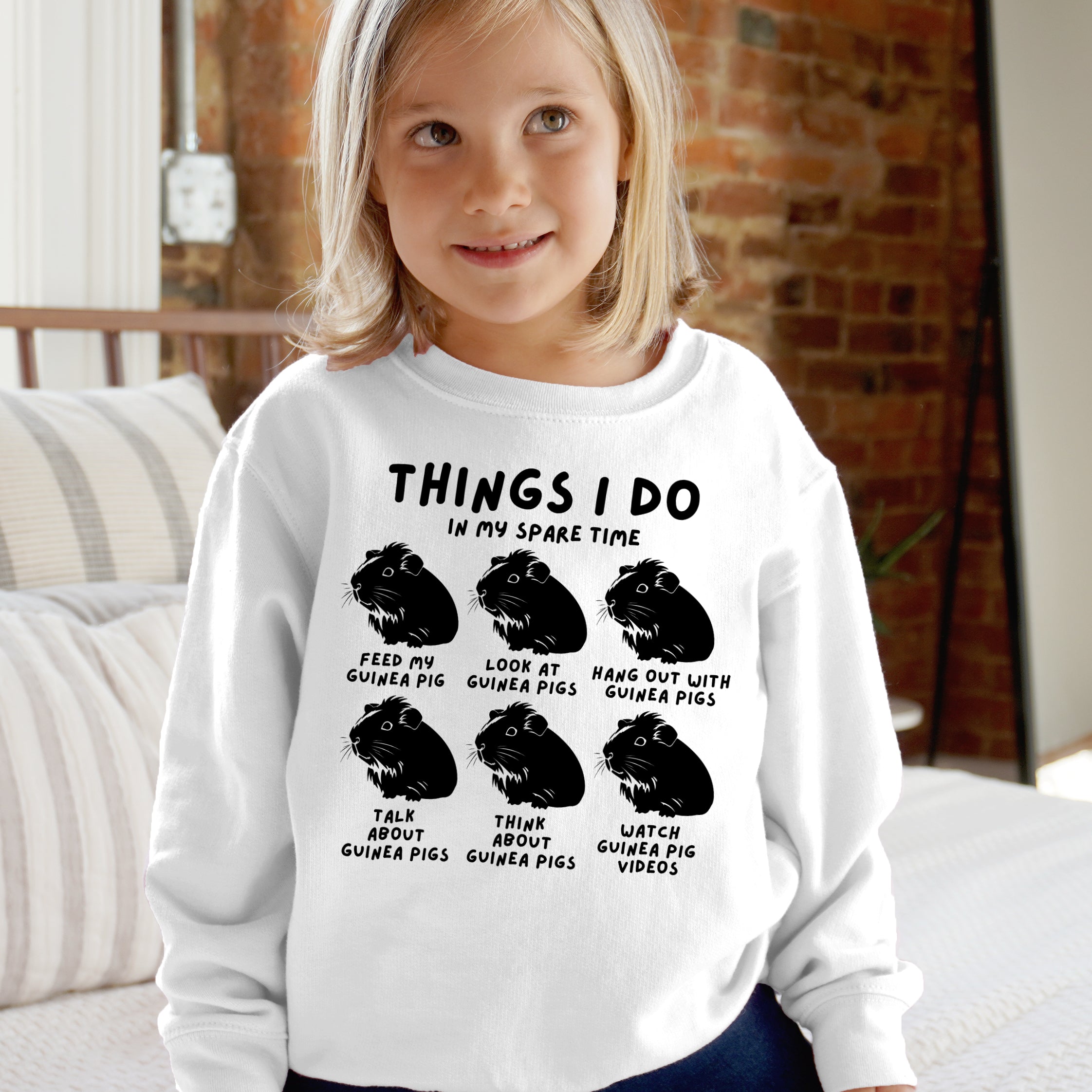 Child wearing a white sweatshirt with text and guinea pig illustrations