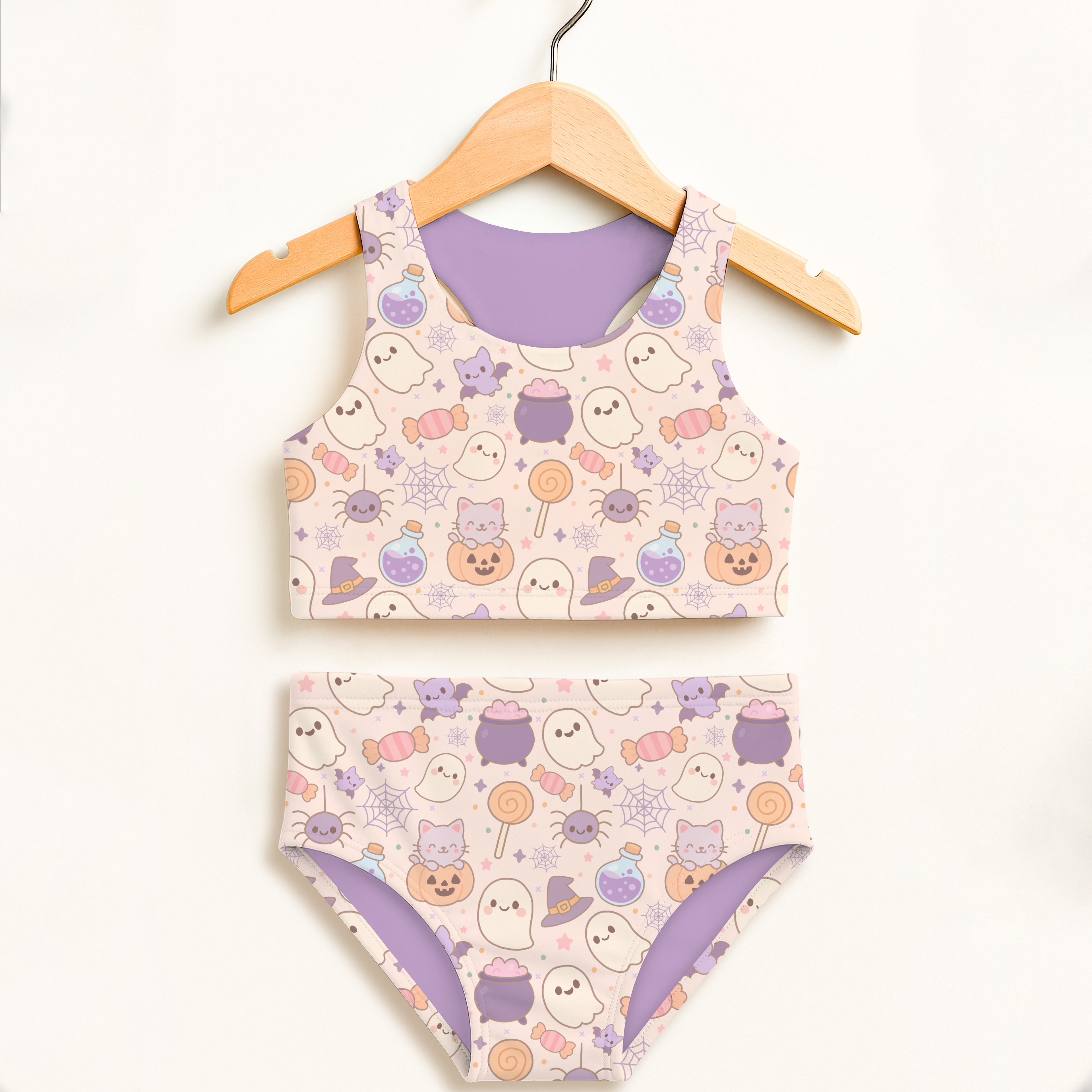 Girls pastel halloween two piece swimsuit with pastel pink base purple accents featuring ghosts cats pumpkins and candy designs