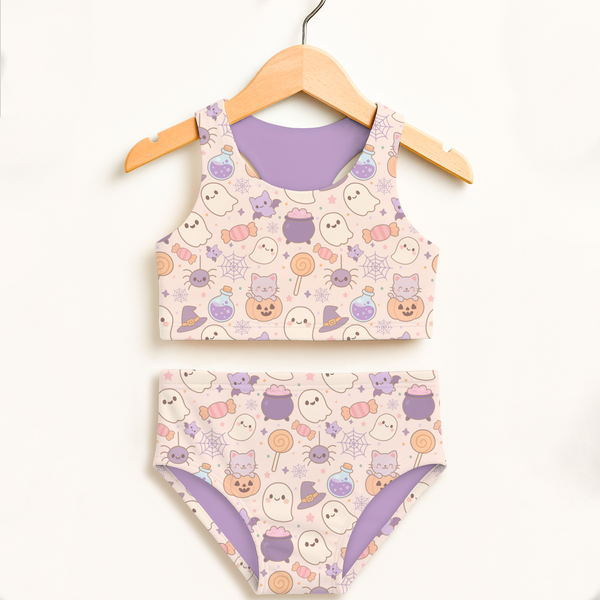 Girls pastel halloween two piece swimsuit with pastel pink base purple accents featuring ghosts cats pumpkins and candy designs