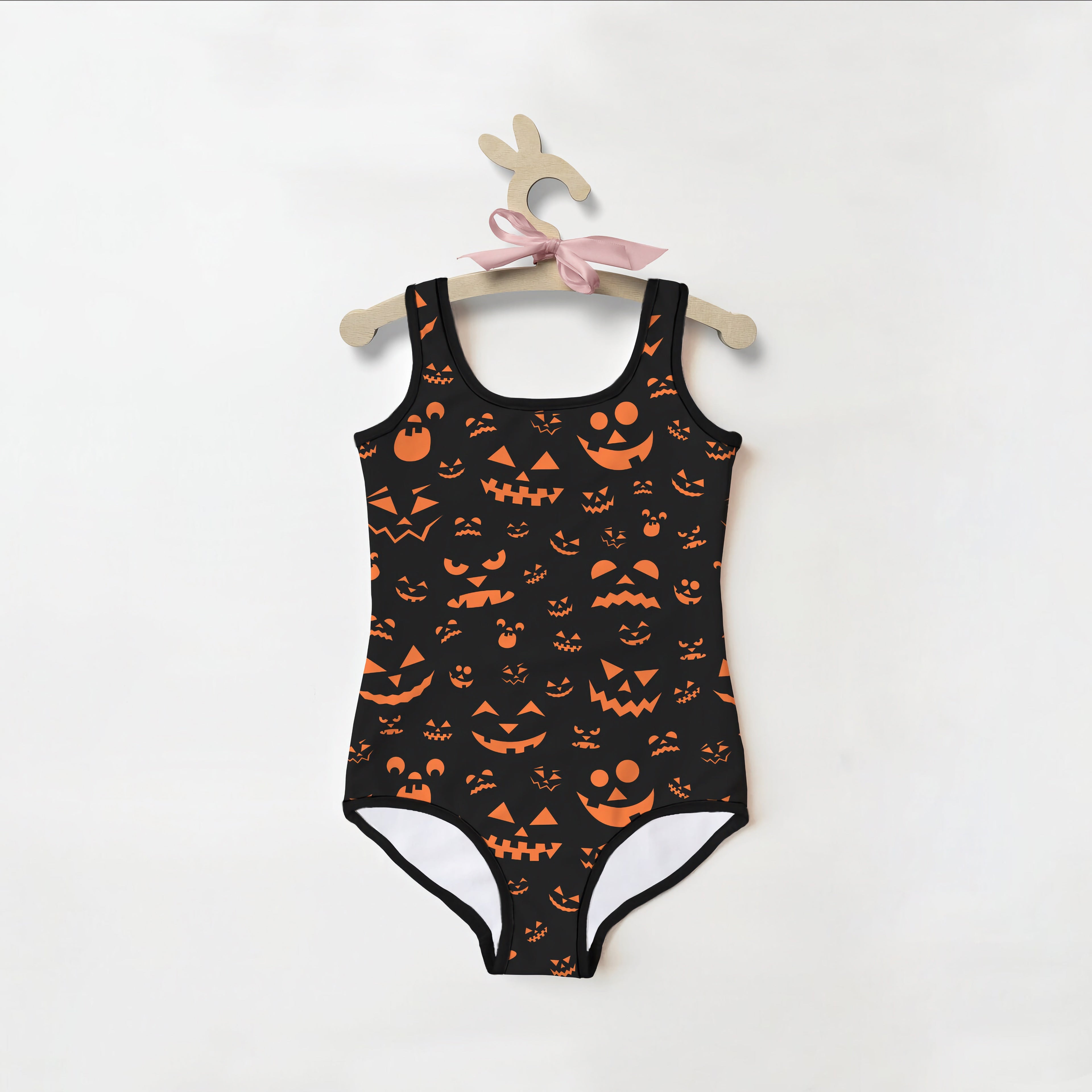 Girls jack-o-lantern faces halloween swimsuit in black with orange pumpkin prints and white leg lining featuring a square neckline