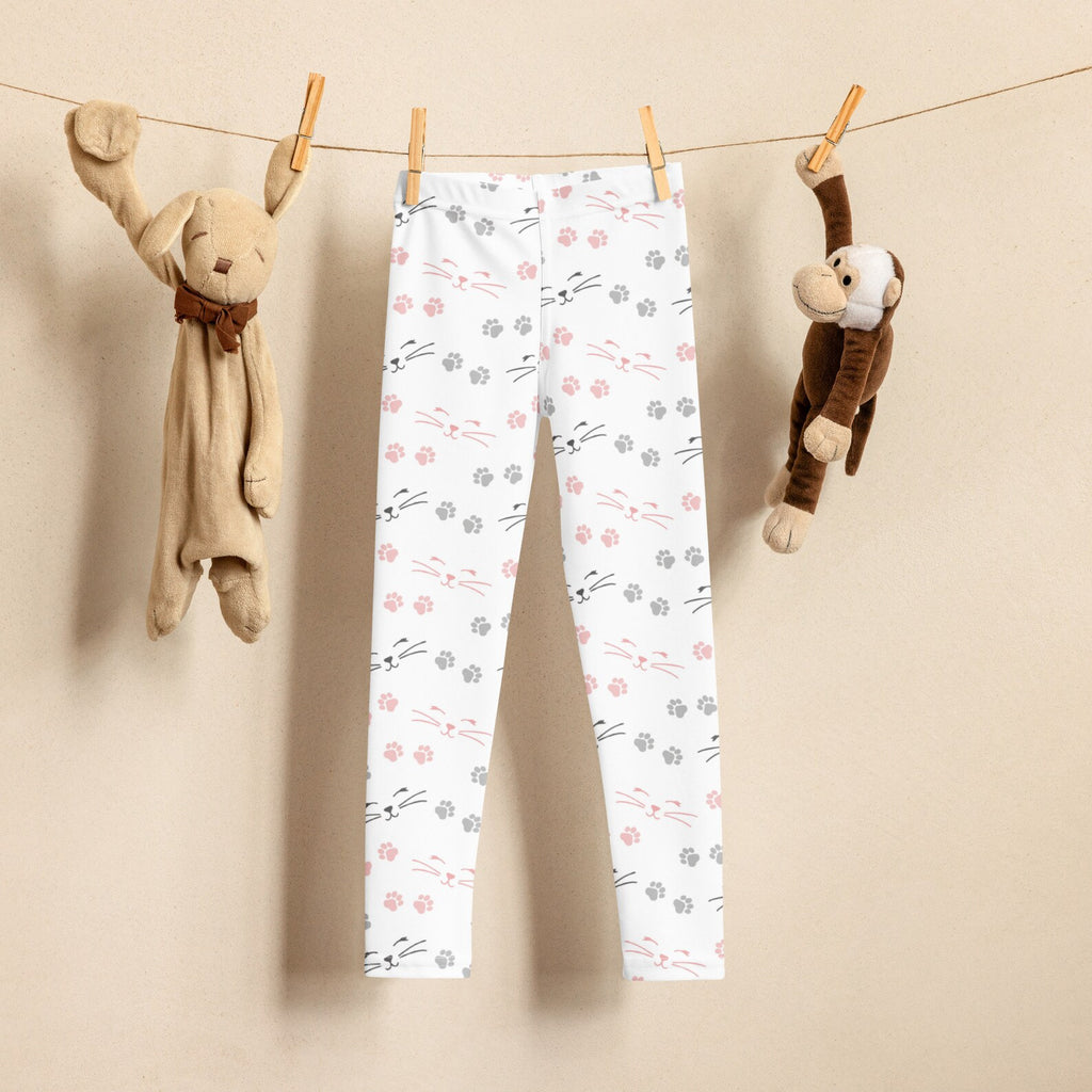 A pair of white leggings with a multicolored paw print pattern, displayed on a clothesline 