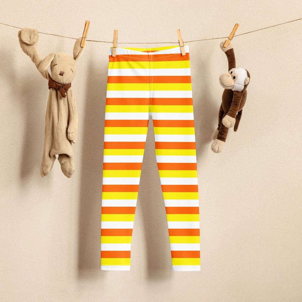 Kids striped halloween candy corn buttery soft leggings in bright orange yellow and white hanging on a clothesline