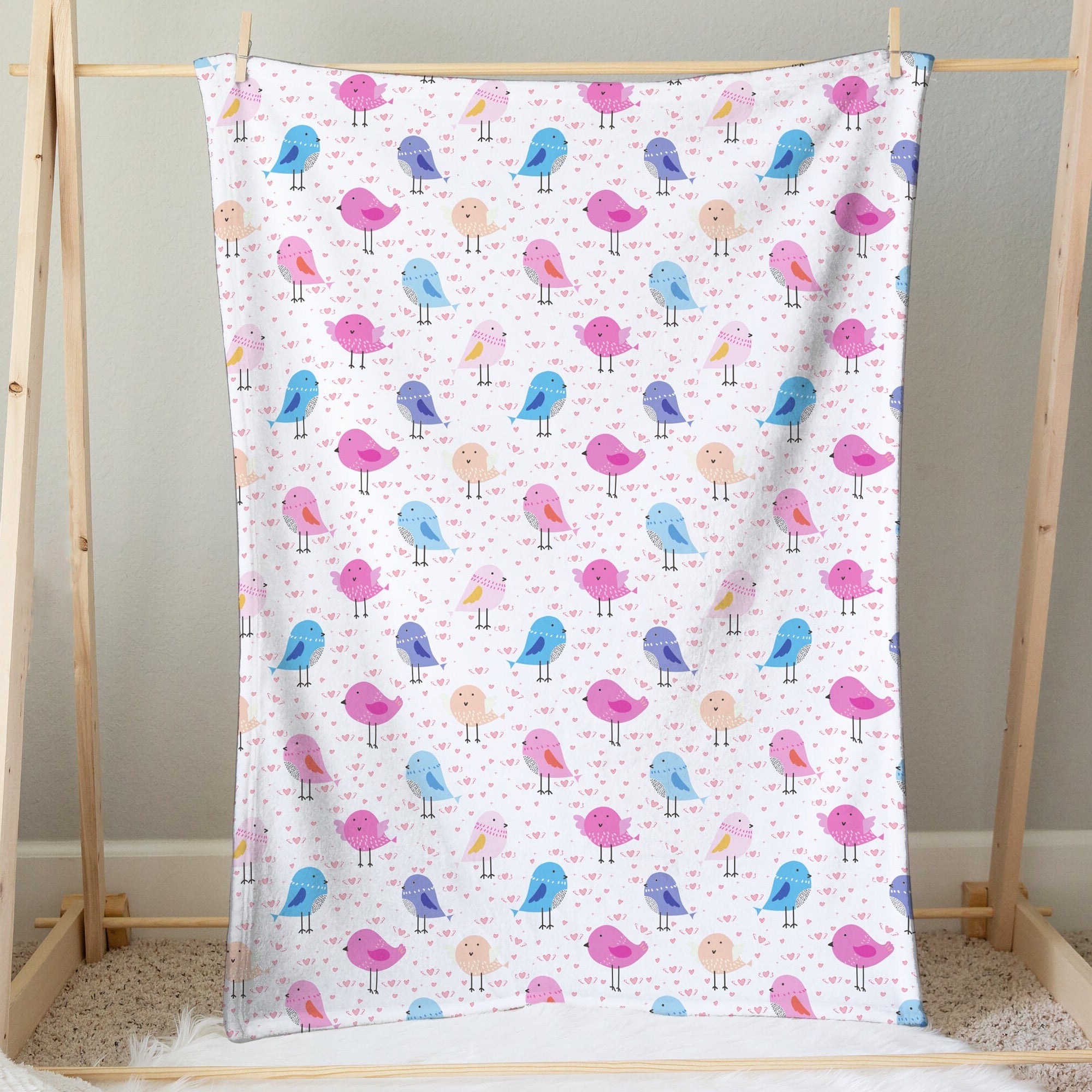 A soft white girls colorful birds blanket with playful pink blue and purple cartoon bird patterns