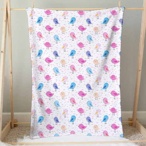 A soft white girls colorful birds blanket with playful pink blue and purple cartoon bird patterns
