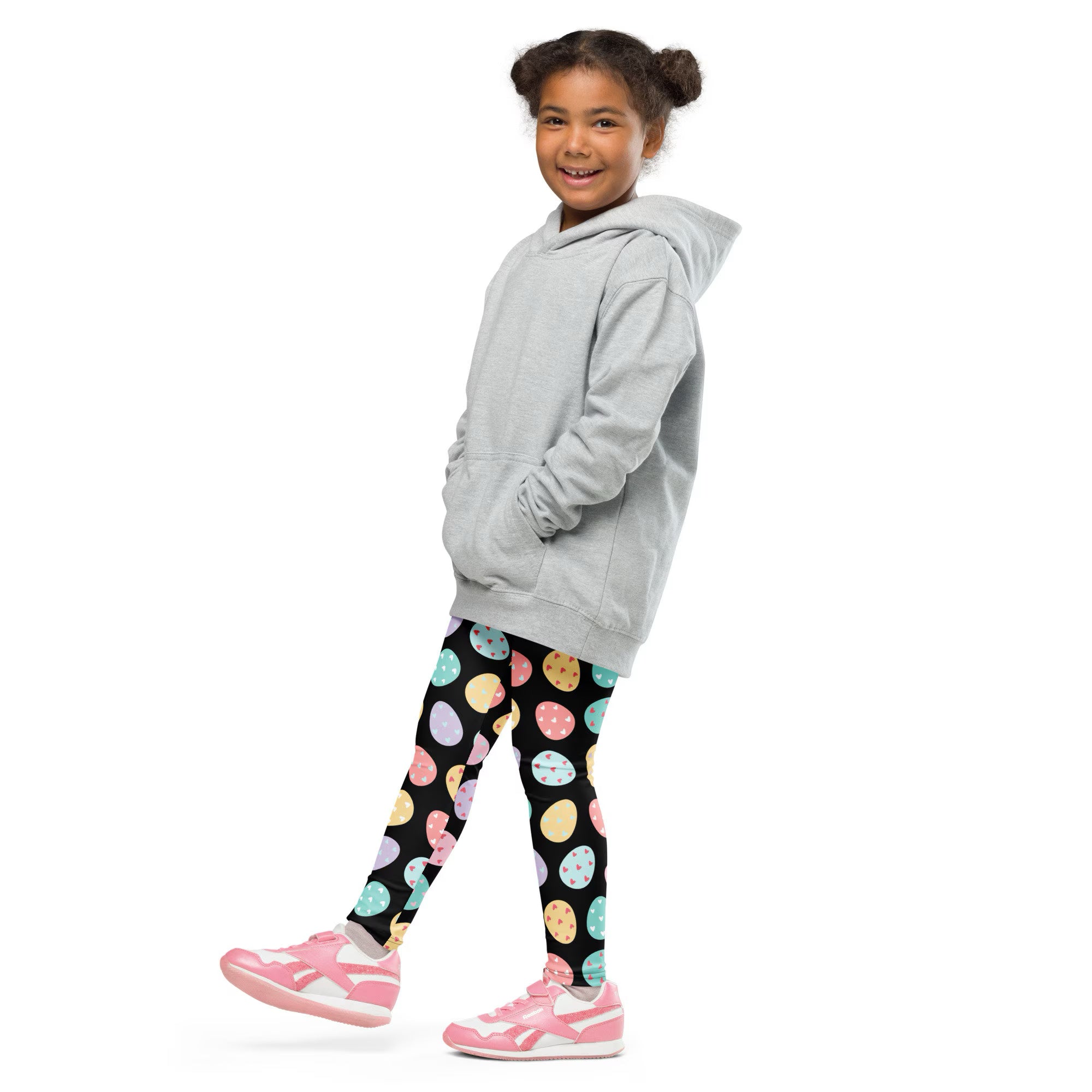 A child wearing kids colorful easter egg buttery soft leggings in black with pastel eggs paired with pink shoes
