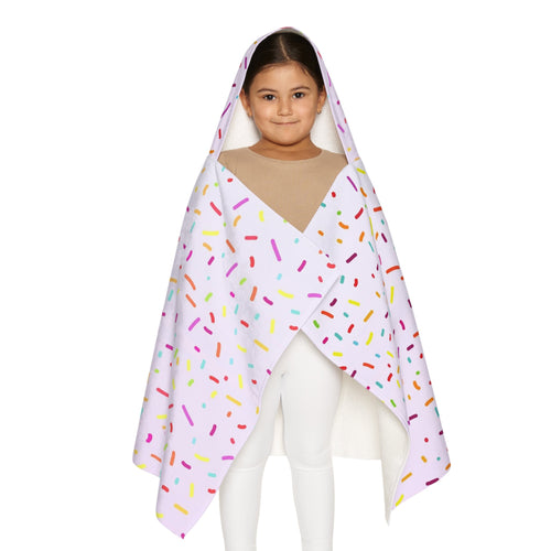 A child wearing a soft white hooded towel with colorful rainbow sprinkles for bath and beach use