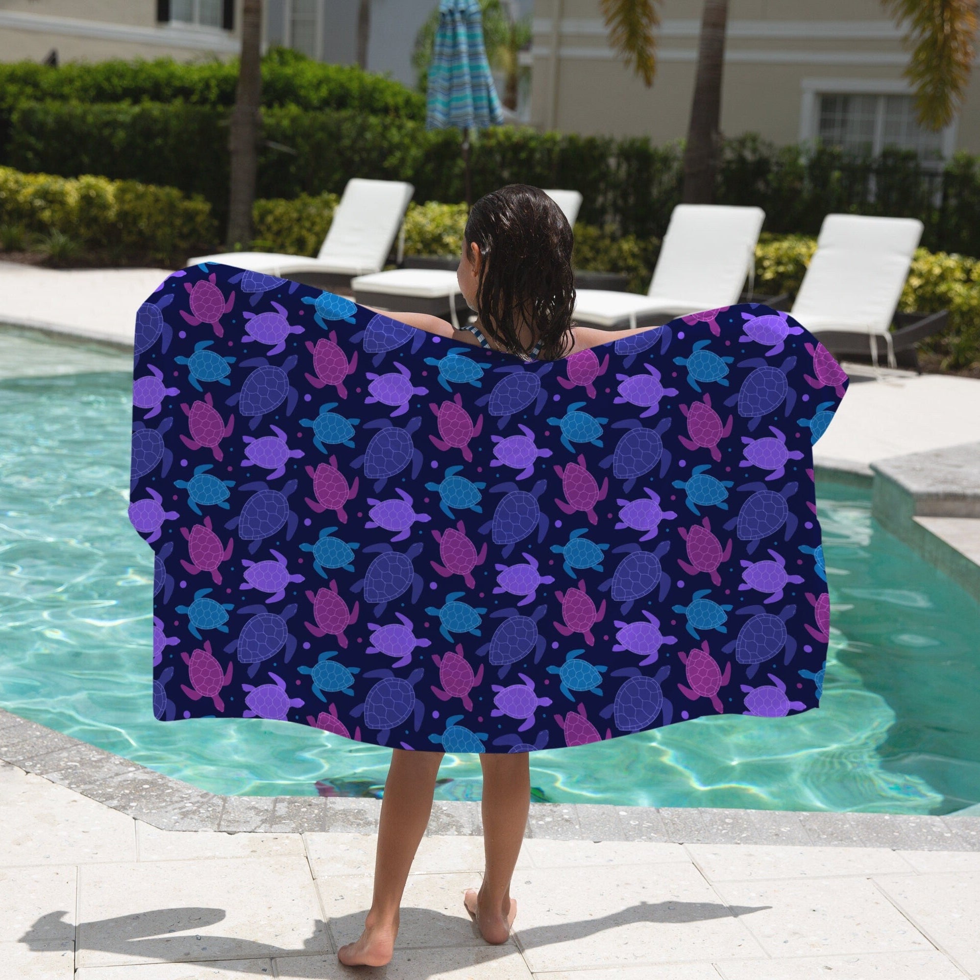 A vibrant navy blue kids beach towel with a playful purple and teal sea turtle pattern for fun beach use