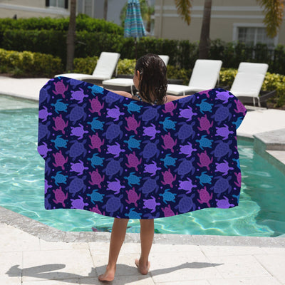 A vibrant navy blue kids beach towel with a playful purple and teal sea turtle pattern for fun beach use