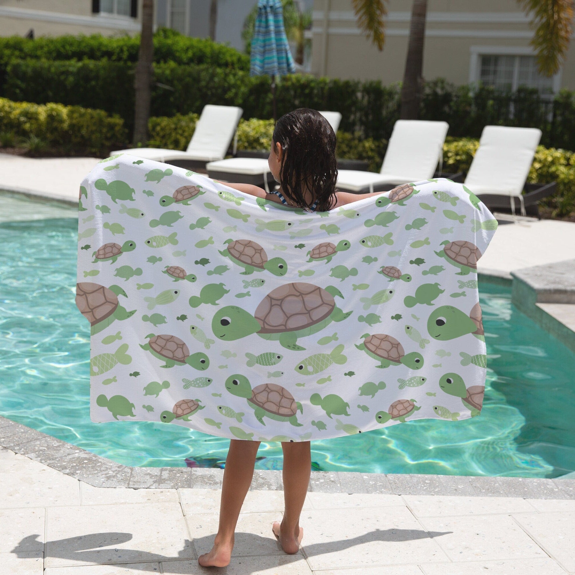 White beach towel featuring a playful pattern of green and brown turtles swimming among small fish for kids