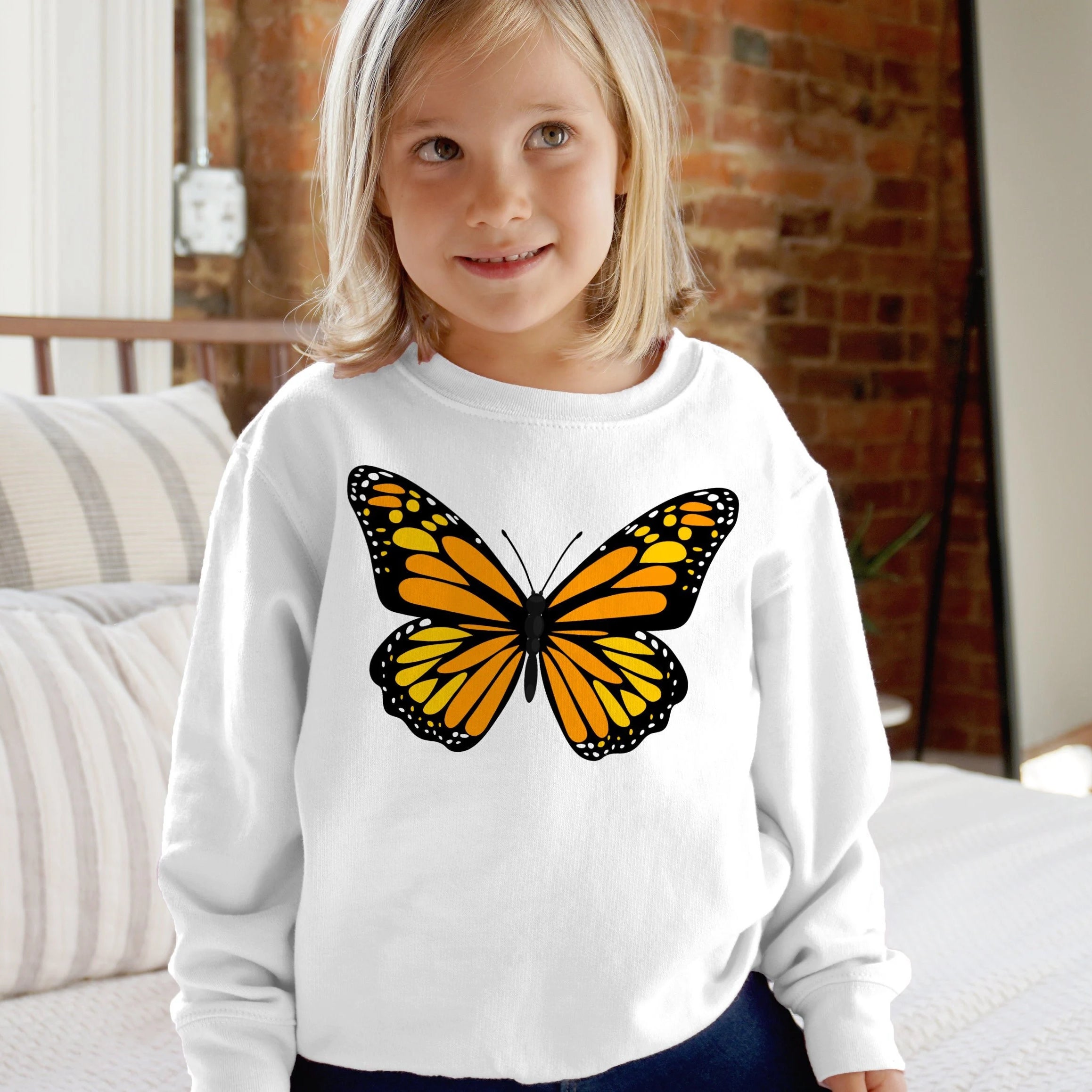 White kids long-sleeved sweatshirt with a vibrant orange and black monarch butterfly graphic on the front