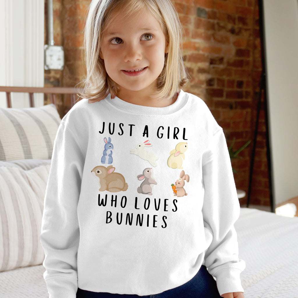 White long-sleeved girls sweatshirt with playful just a girl who loves bunnies graphic and colorful cartoon bunnies