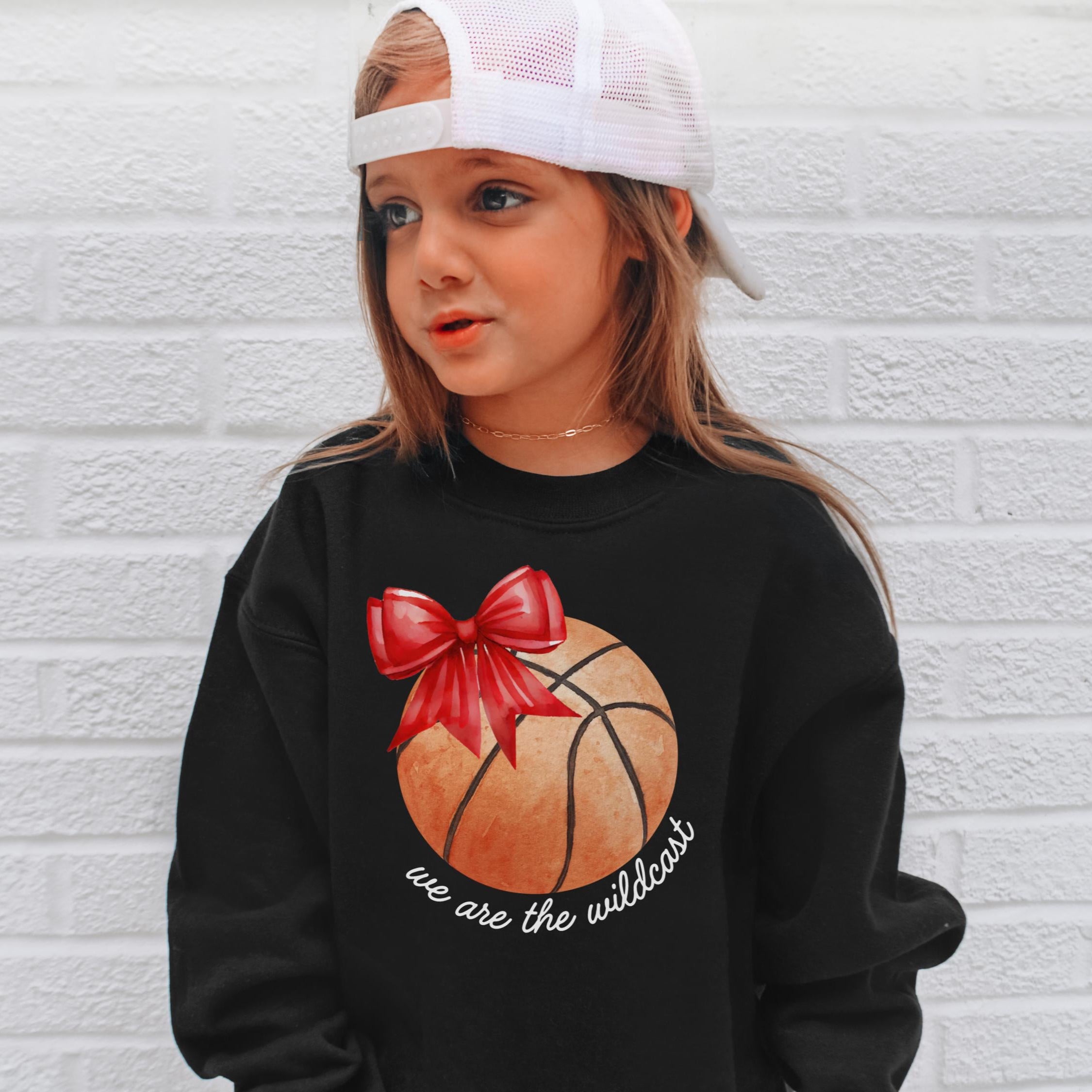 Black long-sleeved sweatshirt with orange basketball graphic red bow and white we are the wildest text for kids basketball fans