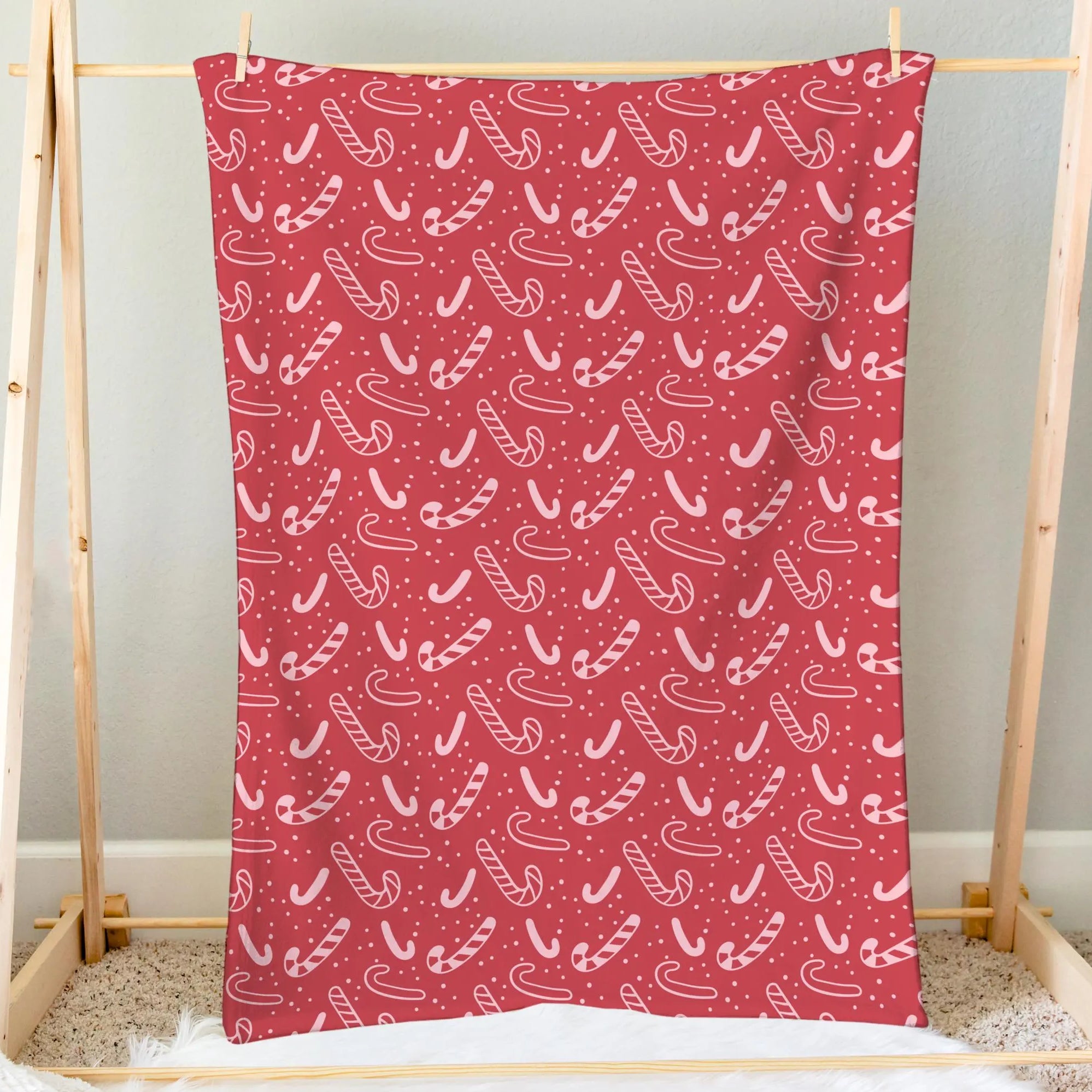 Red candy cane christmas blanket made of soft fabric featuring a repeating pattern of white candy canes and dots