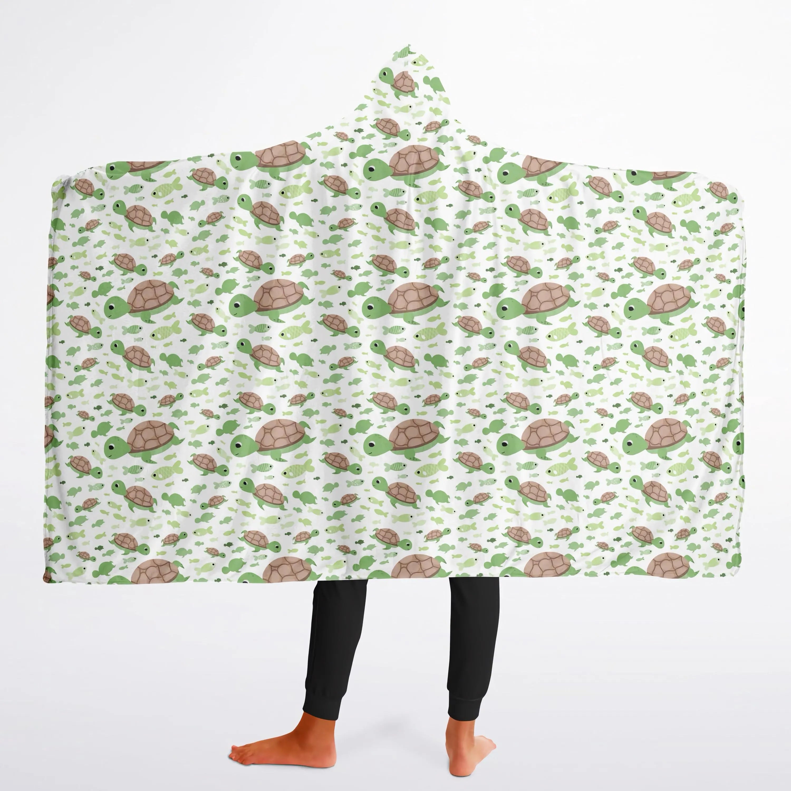 A cozy white hooded wearable blanket for kids featuring a playful green and brown sea turtle pattern