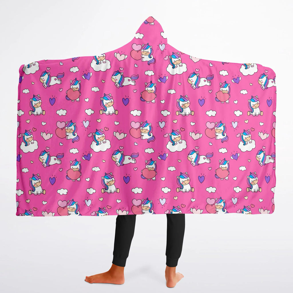 A vibrant pink girls hooded wearable blanket with cartoon unicorns hearts and clouds pattern for cozy wear