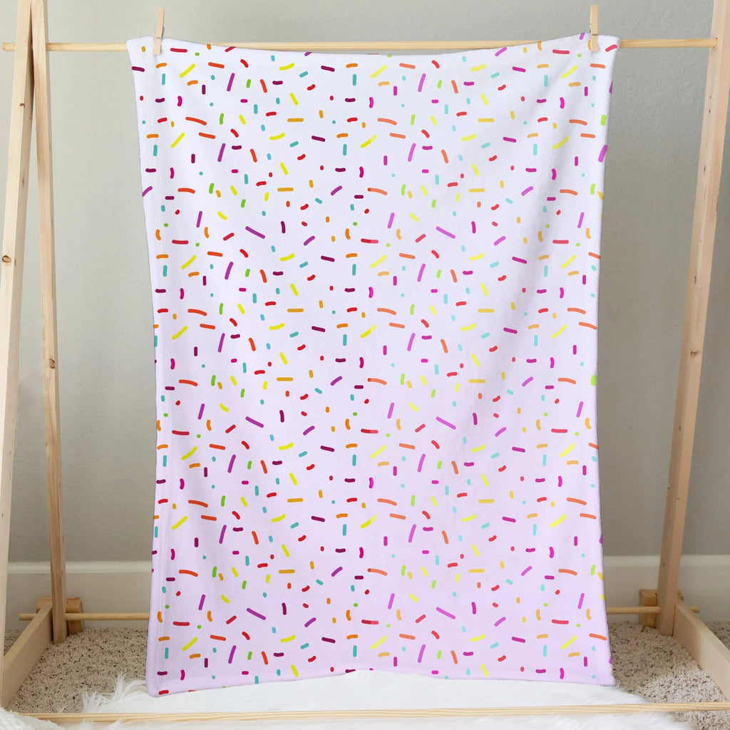 A soft white girls colorful sprinkles ice cream blanket with playful multicolored pink yellow green blue and orange dots