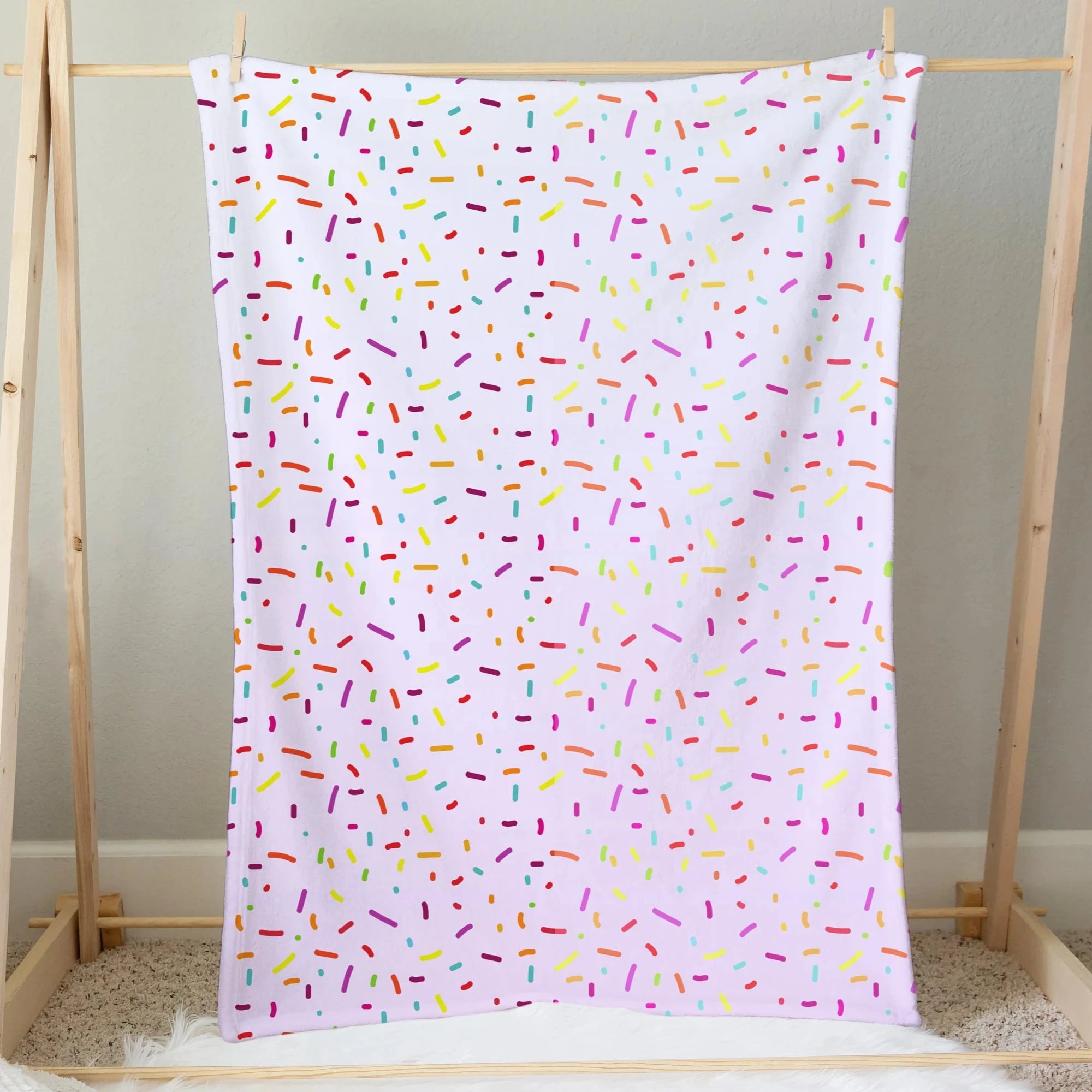 A soft white girls colorful sprinkles ice cream blanket with playful multicolored pink yellow green blue and orange dots