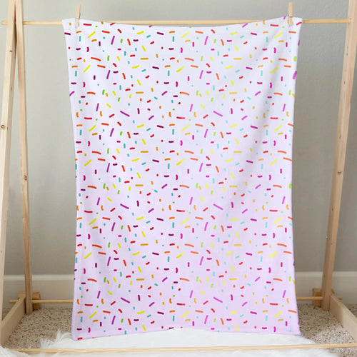 A soft white girls colorful sprinkles ice cream blanket with playful multicolored pink yellow green blue and orange dots