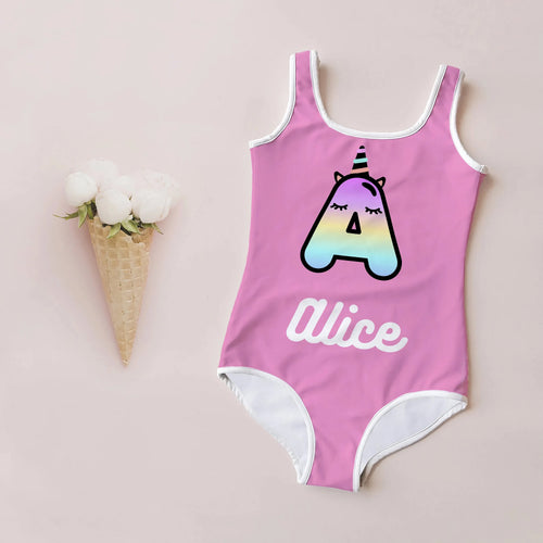 Pink one-piece swimsuit with white trim featuring a rainbow gradient unicorn initial a and alice name in white script