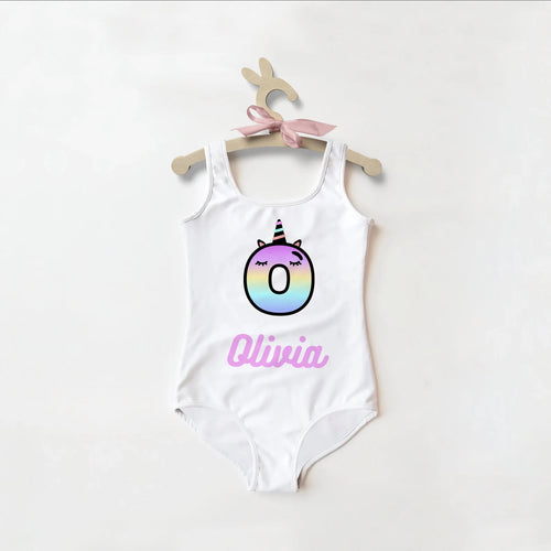 White one-piece swimsuit for girls with rainbow unicorn number zero and pink olivia name in script custom design