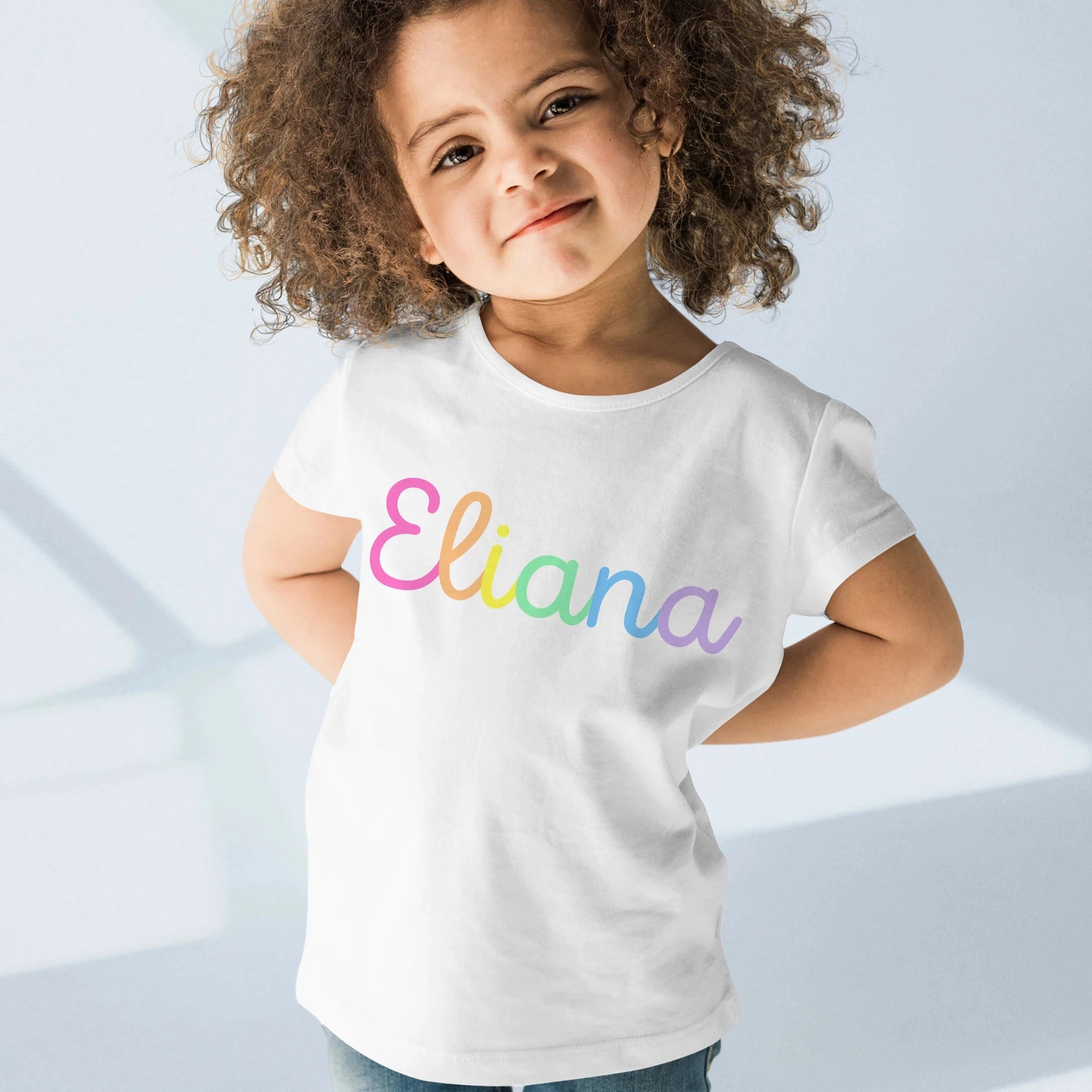 White cotton girls custom name t-shirt with eliana printed in rainbow gradient script across the chest