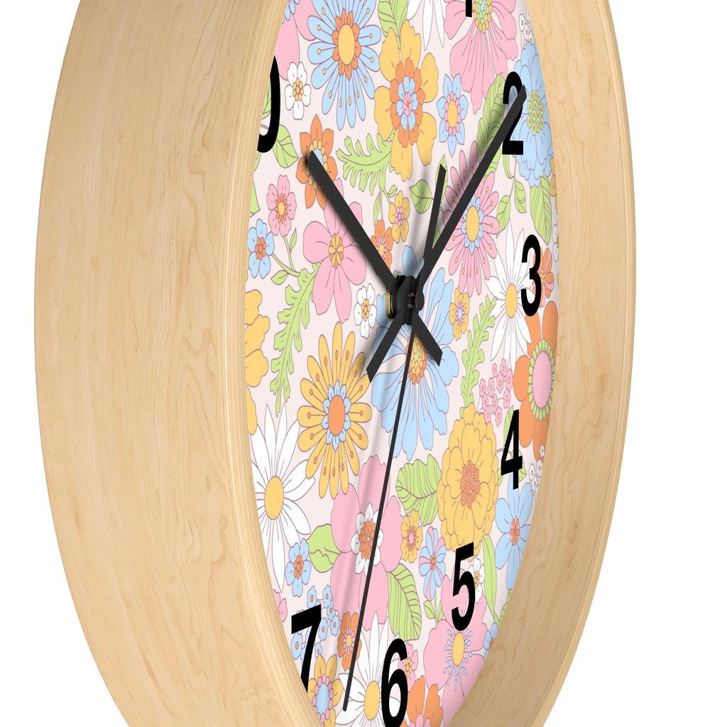 A round silent wood wall clock with light wood frame and colorful retro flowers in pink blue yellow and white