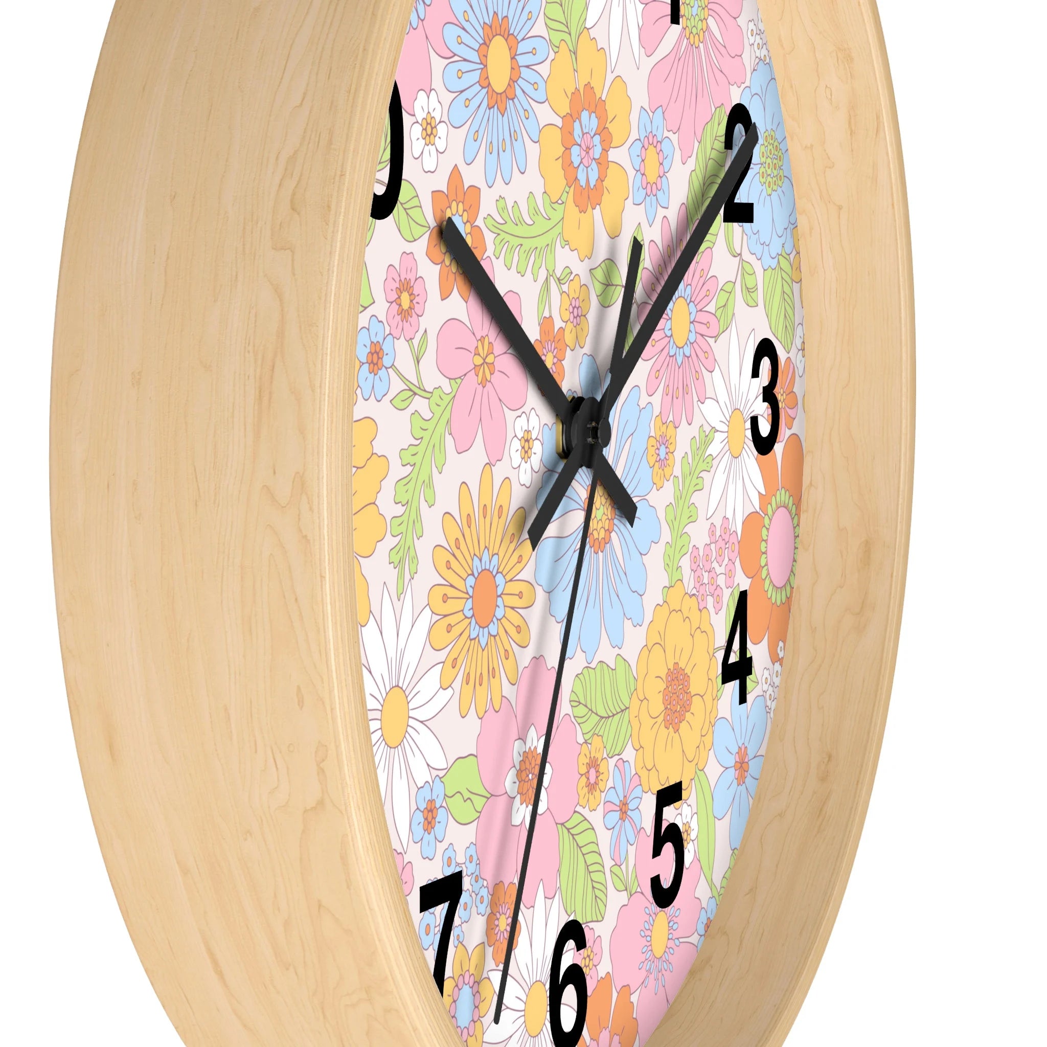 A round silent wood wall clock with light wood frame and colorful retro flowers in pink blue yellow and white