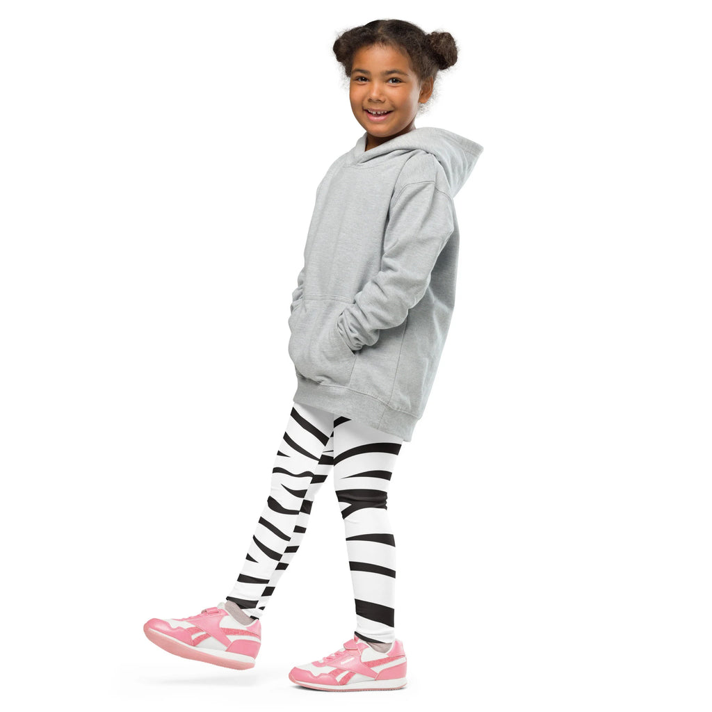 A young girl wearing light gray hooded sweatshirt and black and white striped buttery soft kids zebra leggings