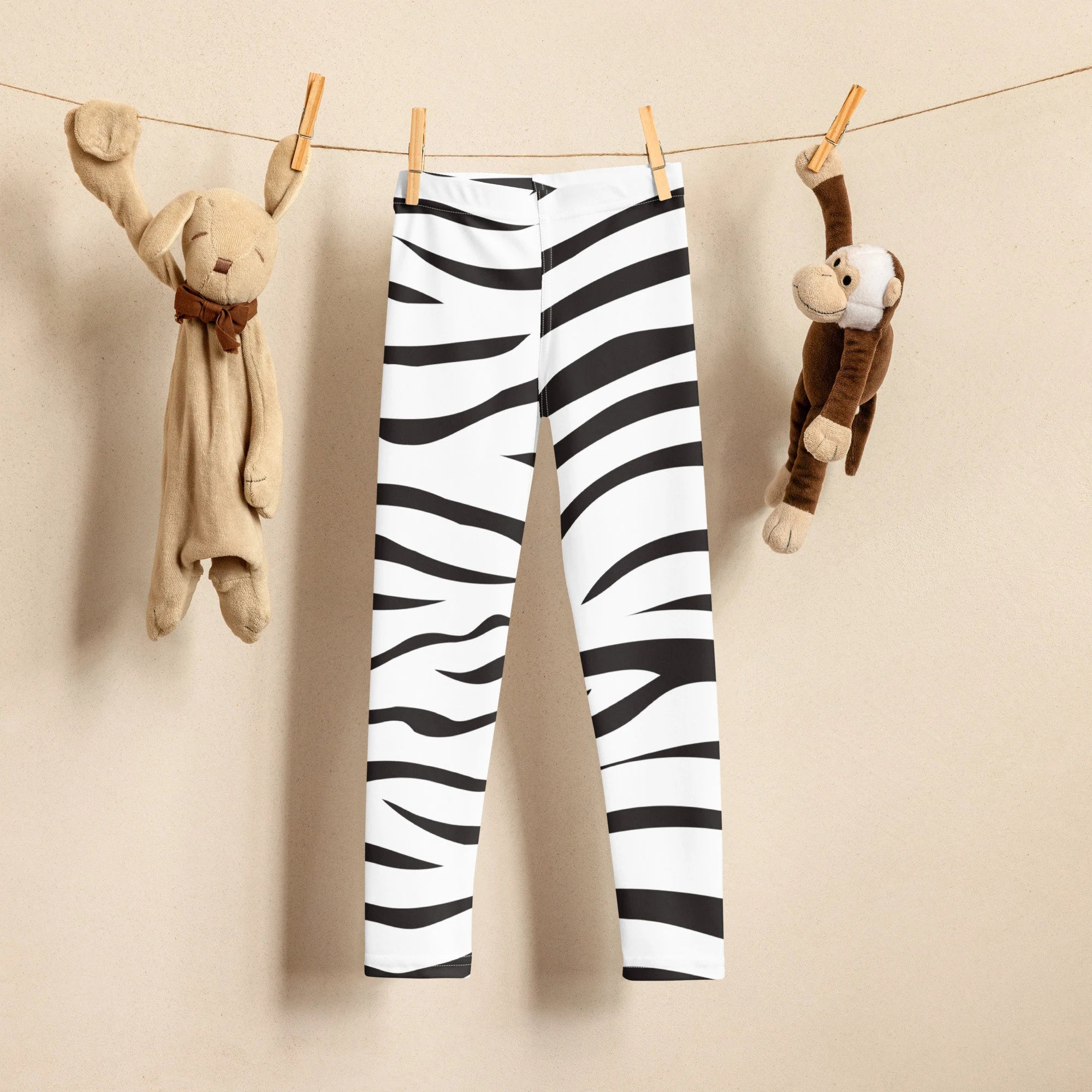 Kids striped zebra buttery soft leggings in white with bold black zebra stripes hanging on a clothesline