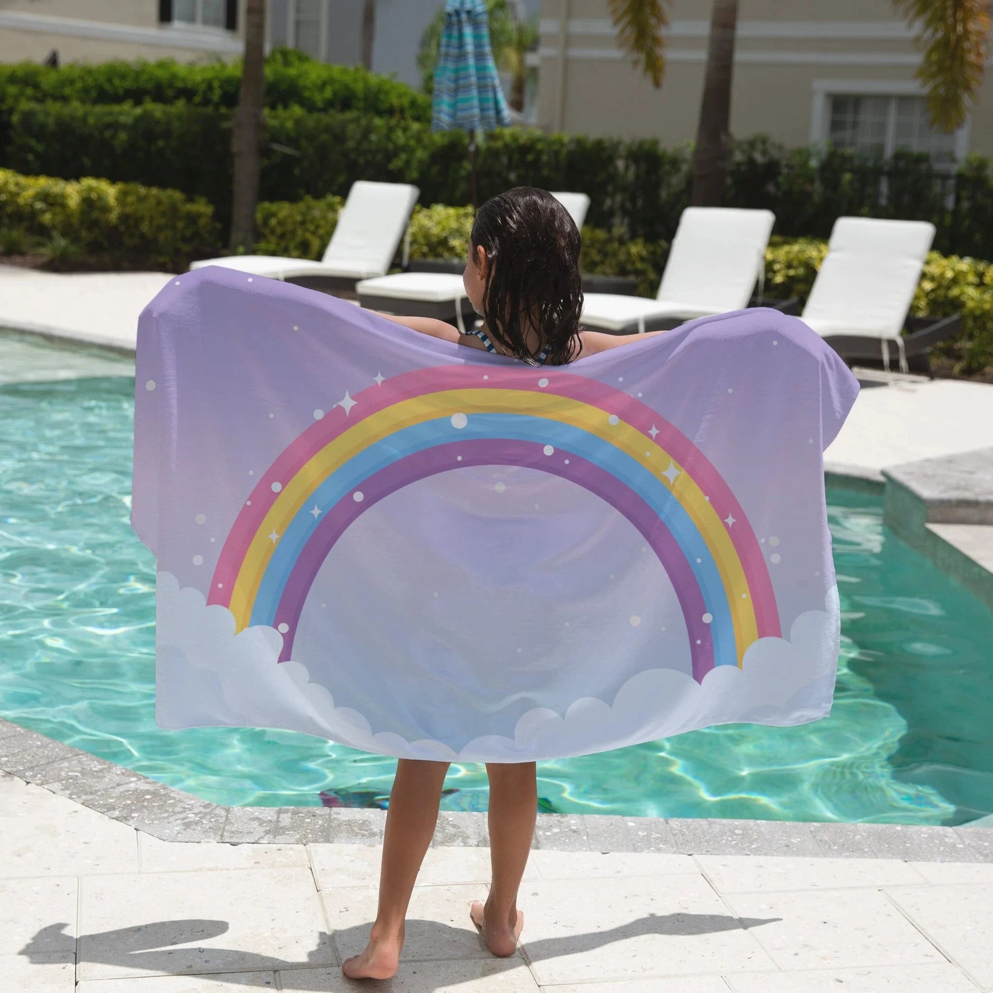 Girls rainbow over clouds towel featuring a lavender color with vibrant rainbow and cloud design for beach use