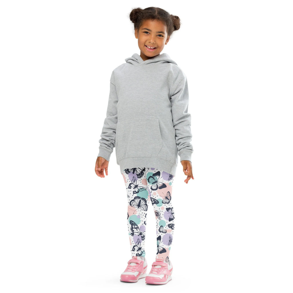 A child wearing girls butterfly buttery soft leggings in pastel butterfly patterns with a light gray hooded sweatshirt