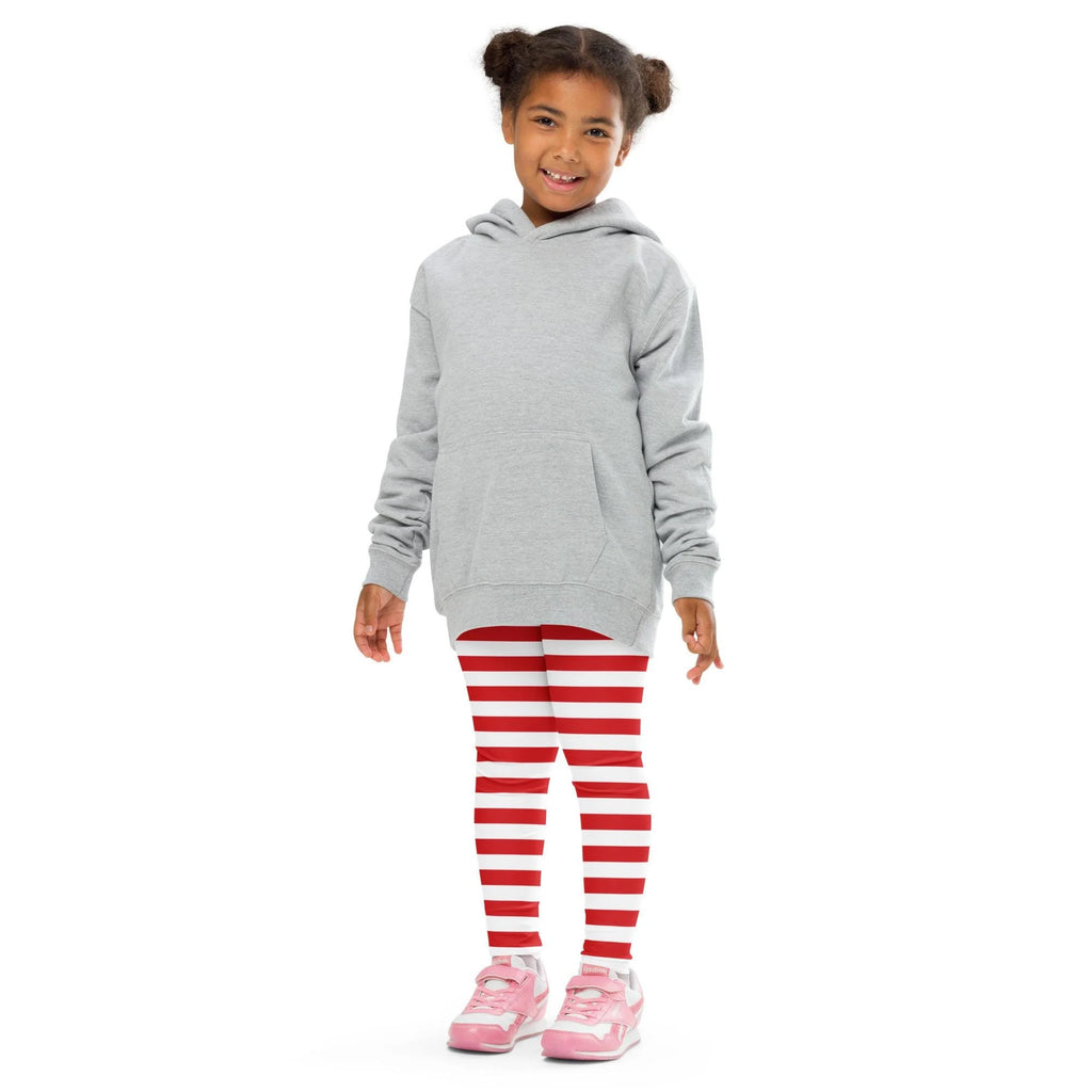 A child wearing red and white striped buttery soft Christmas leggings paired with a light gray hooded sweatshirt