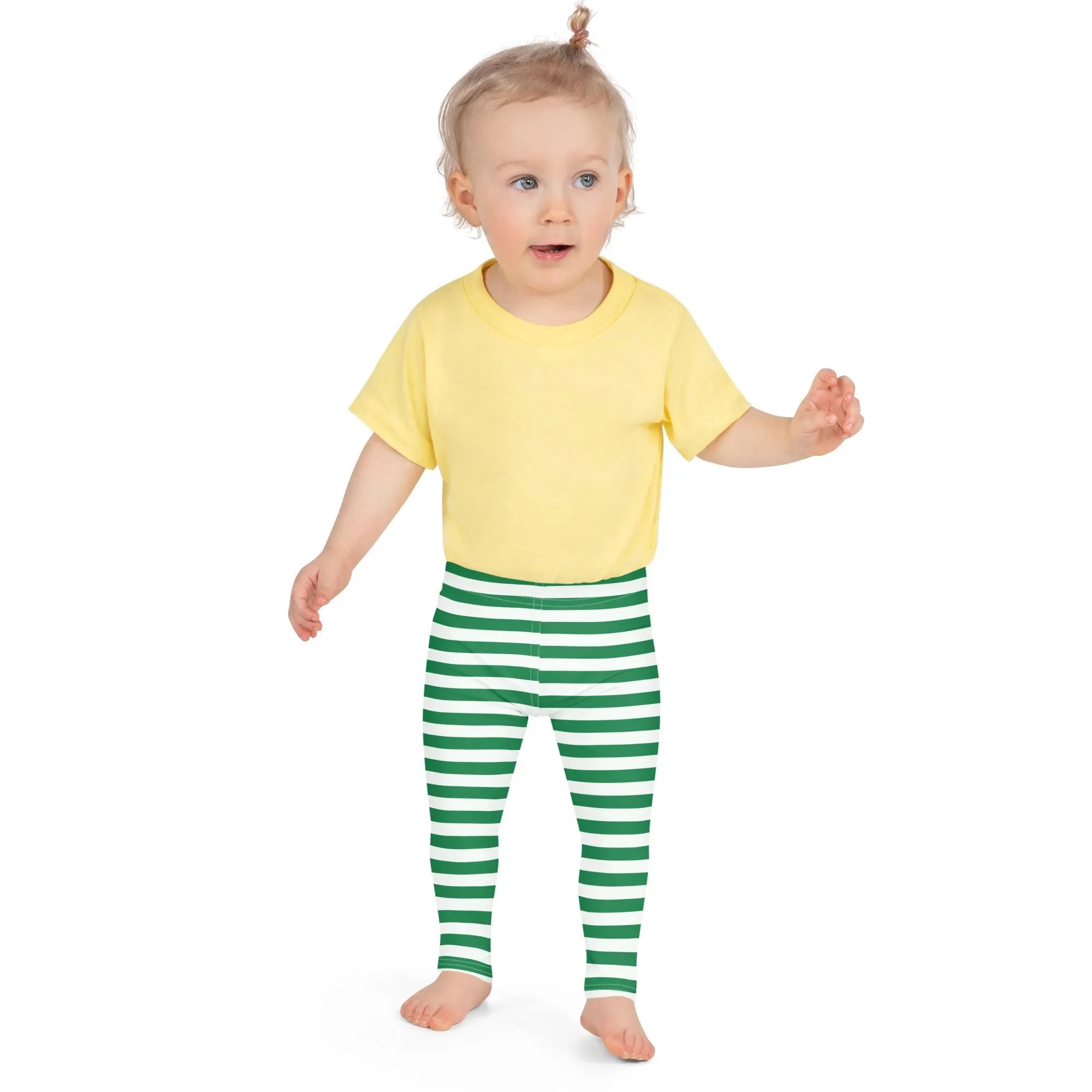 A toddler wearing green striped buttery soft Christmas leggings in green white with yellow short-sleeved t-shirt