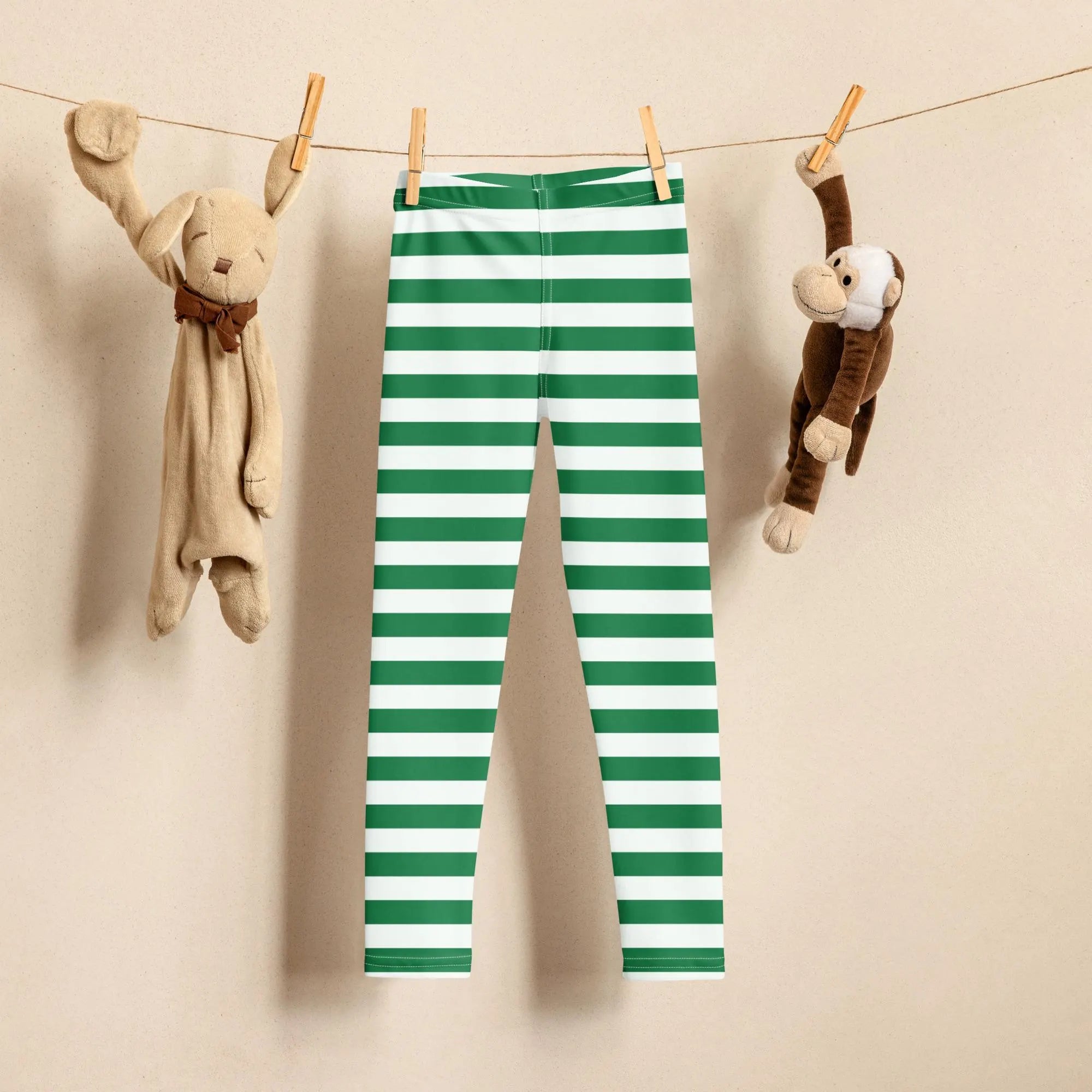 Green and white horizontally striped buttery soft kids Christmas leggings hanging on a clothesline